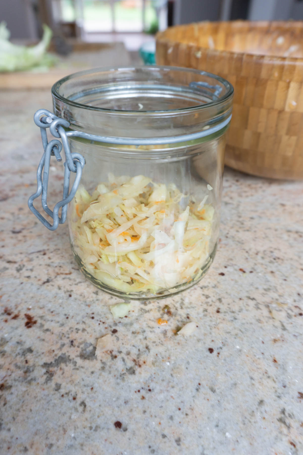 Adding homemade sauerkraut mixture to glass jar