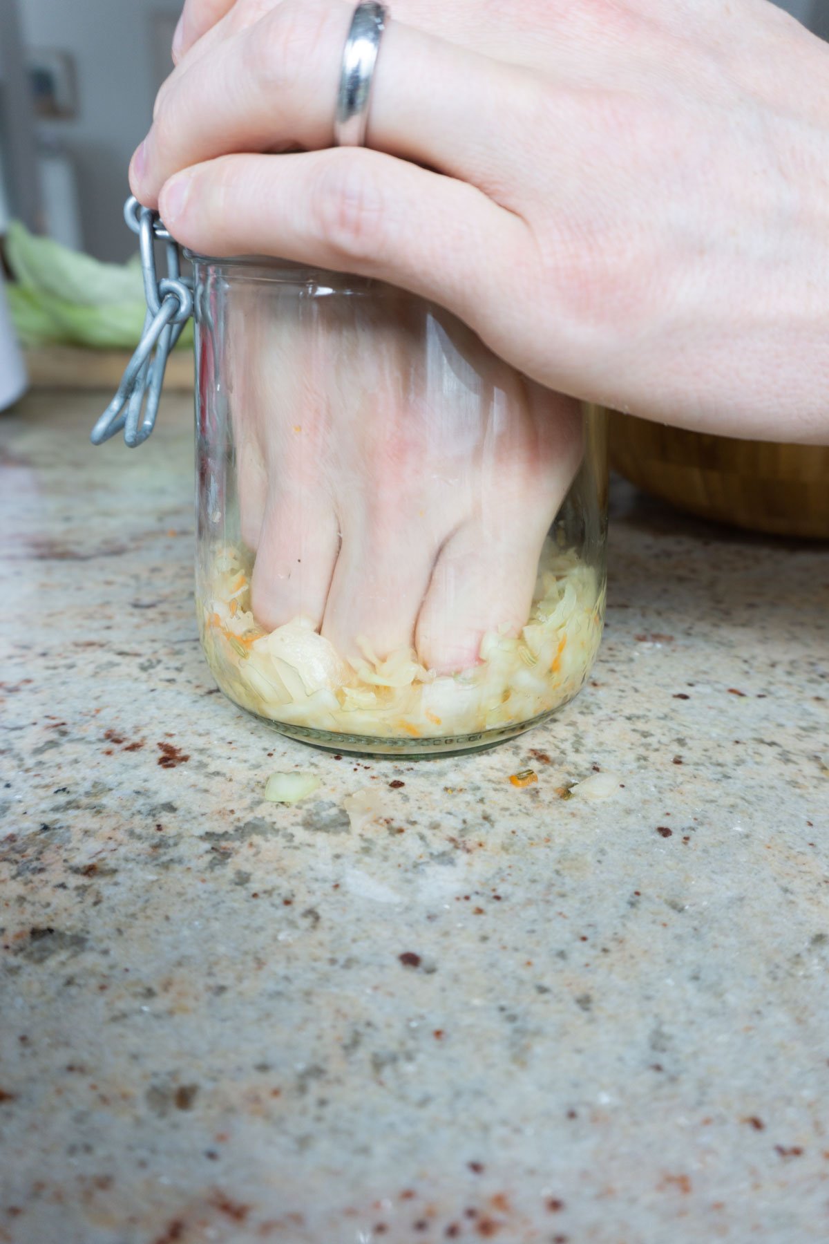 Pressing down homemade sauerkraut in glass jar