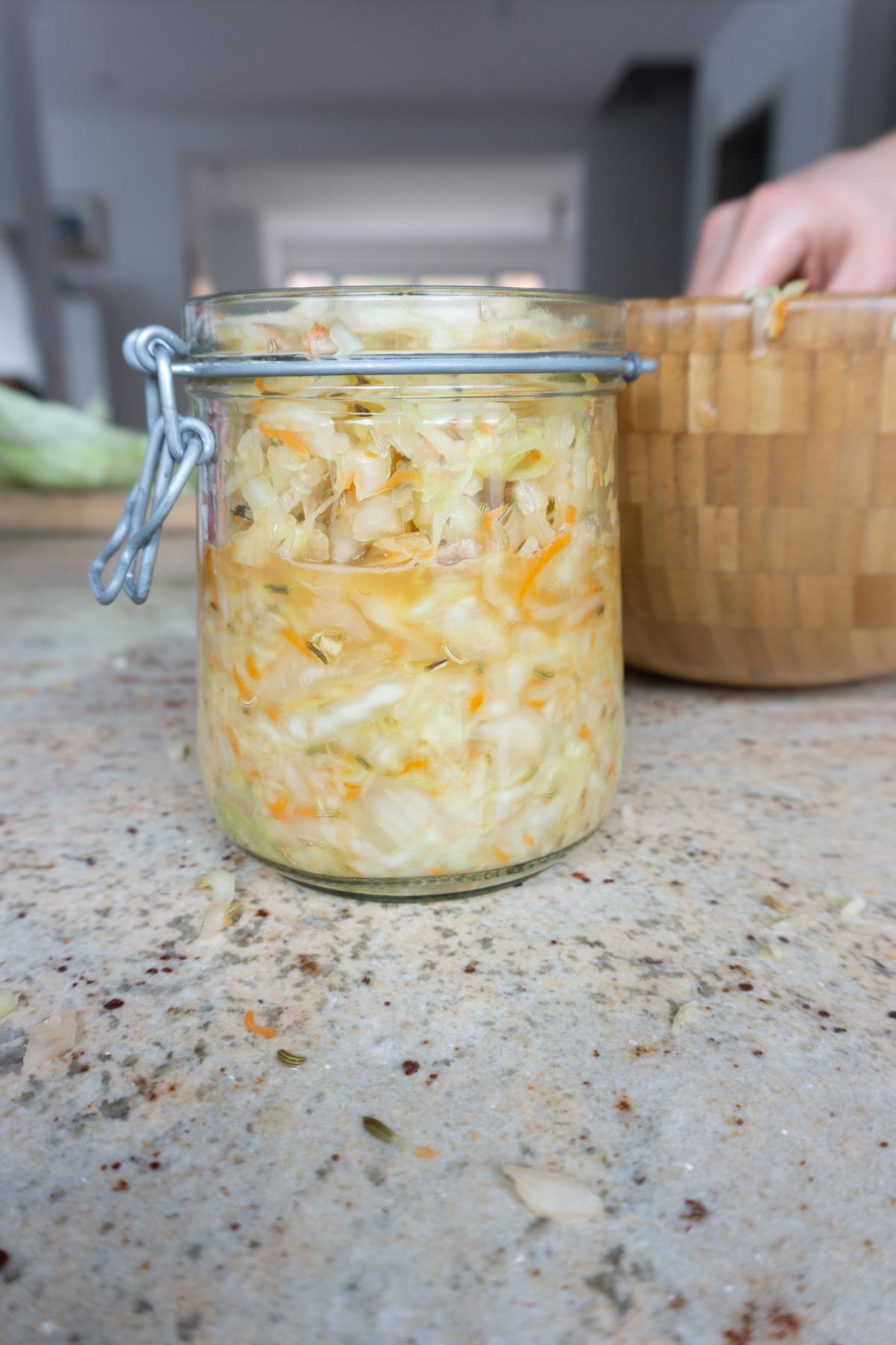Adding homemade sauerkraut mixture to glass jar