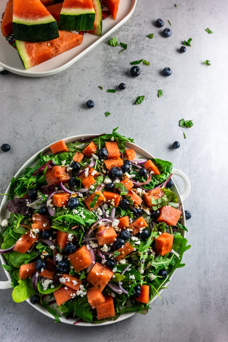 Watermelon Feta Salad with blueberries and mint strewn on a grey background