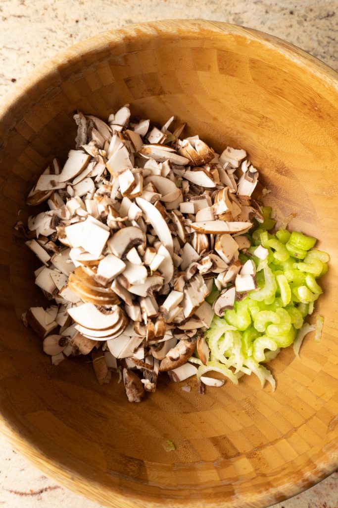 Chopped celery and mushrooms in a wooden salad bowl