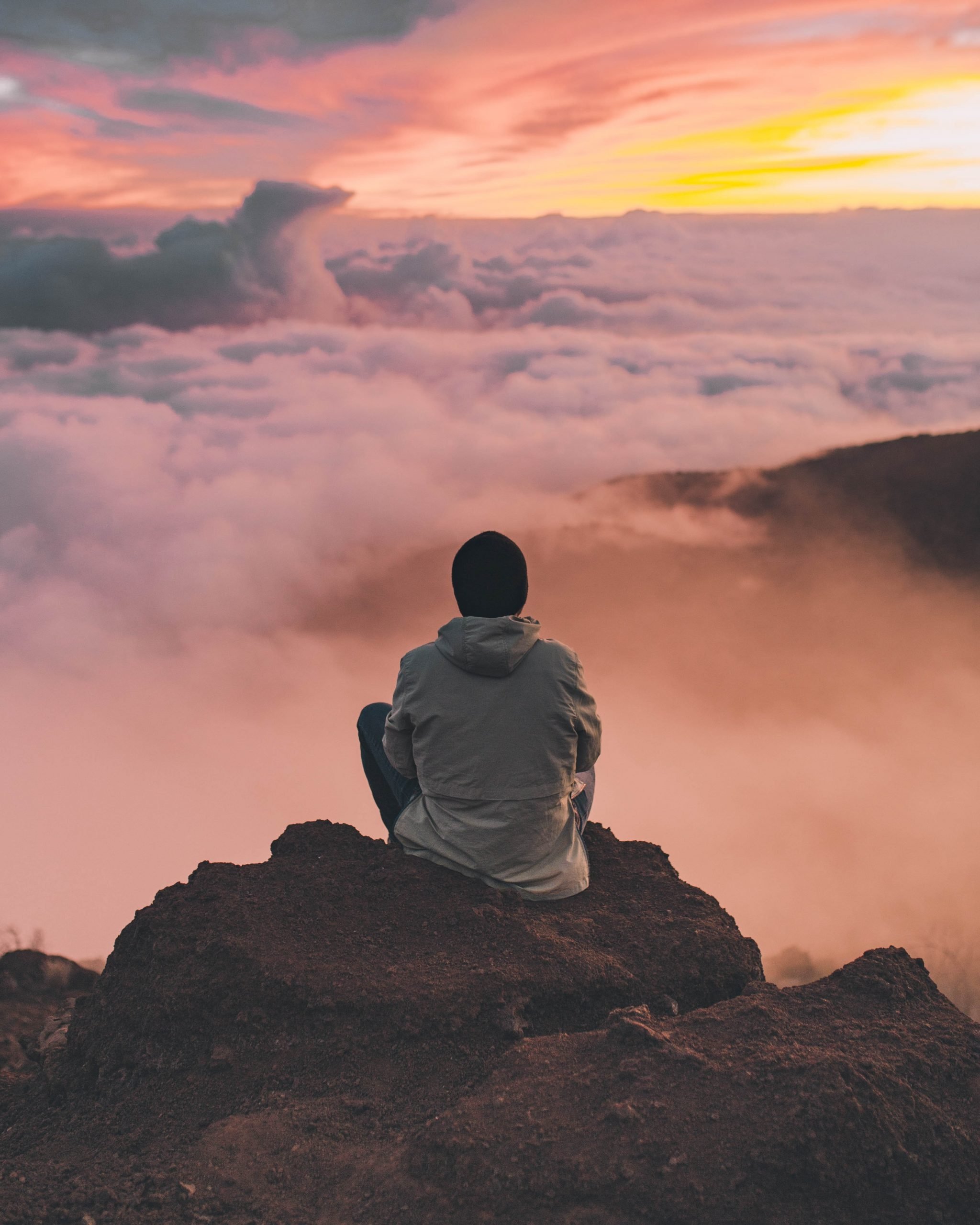 Man sitting on a mountain above the clouds meditating