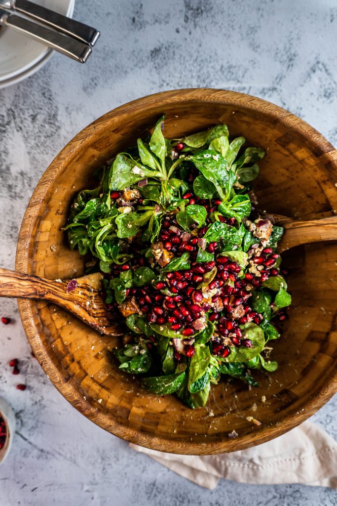 Warming Winter Salad in a wooden bowl with wooden salad tongs stuck into it, photographed from above