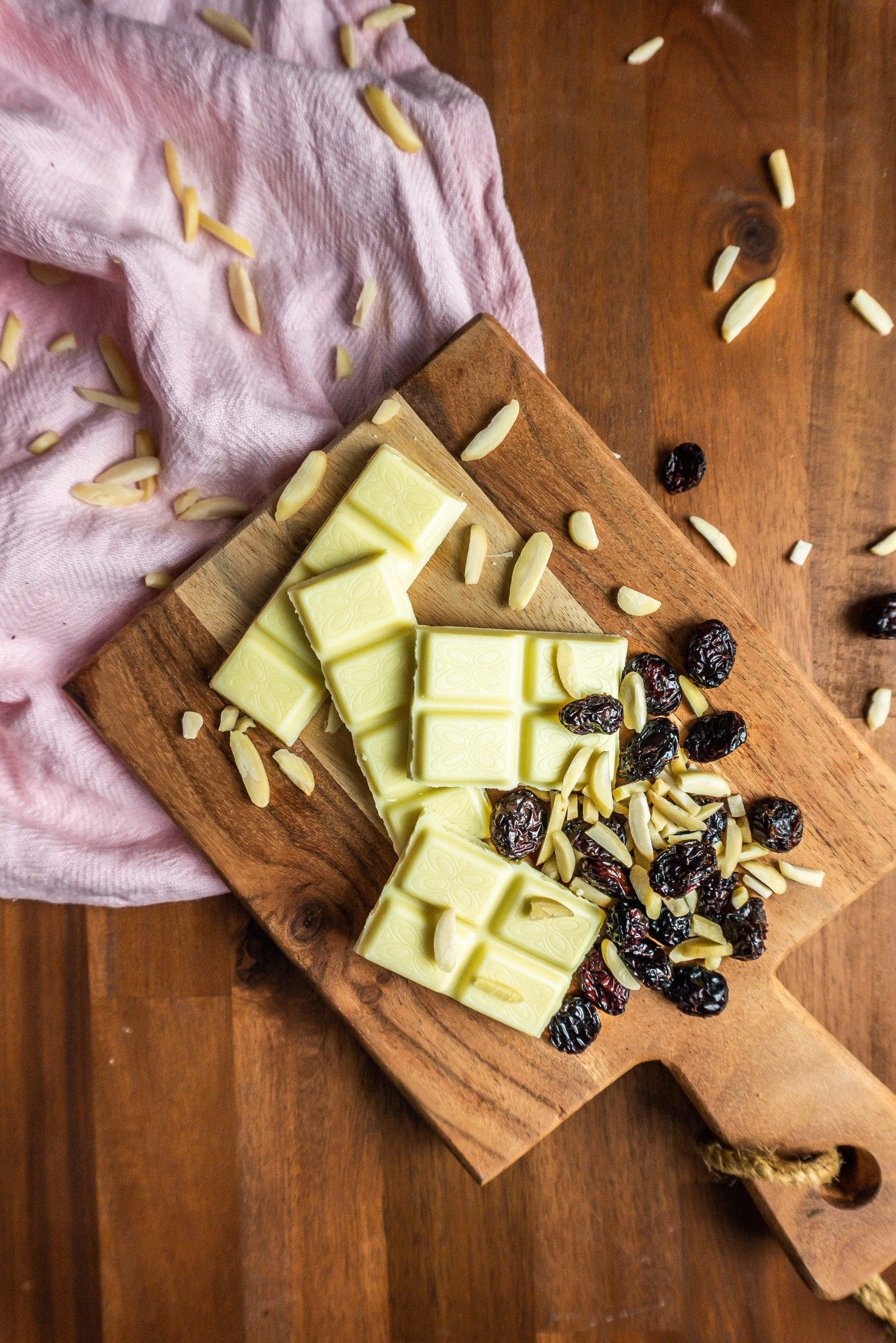 White chocolate, shaved almonds, and cranberries on a small wooden board