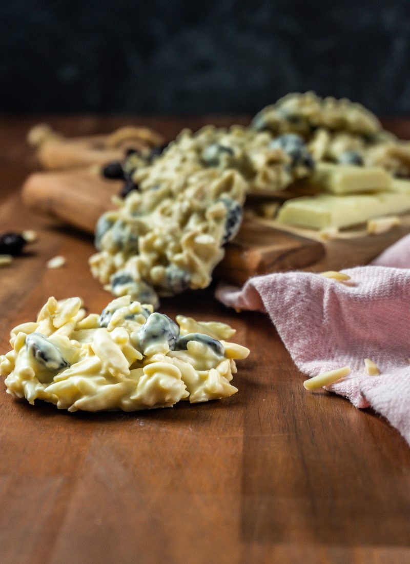 Shaved Almond and Cranberry White Chocolate Cookie in focus with more cookies scattered in the background