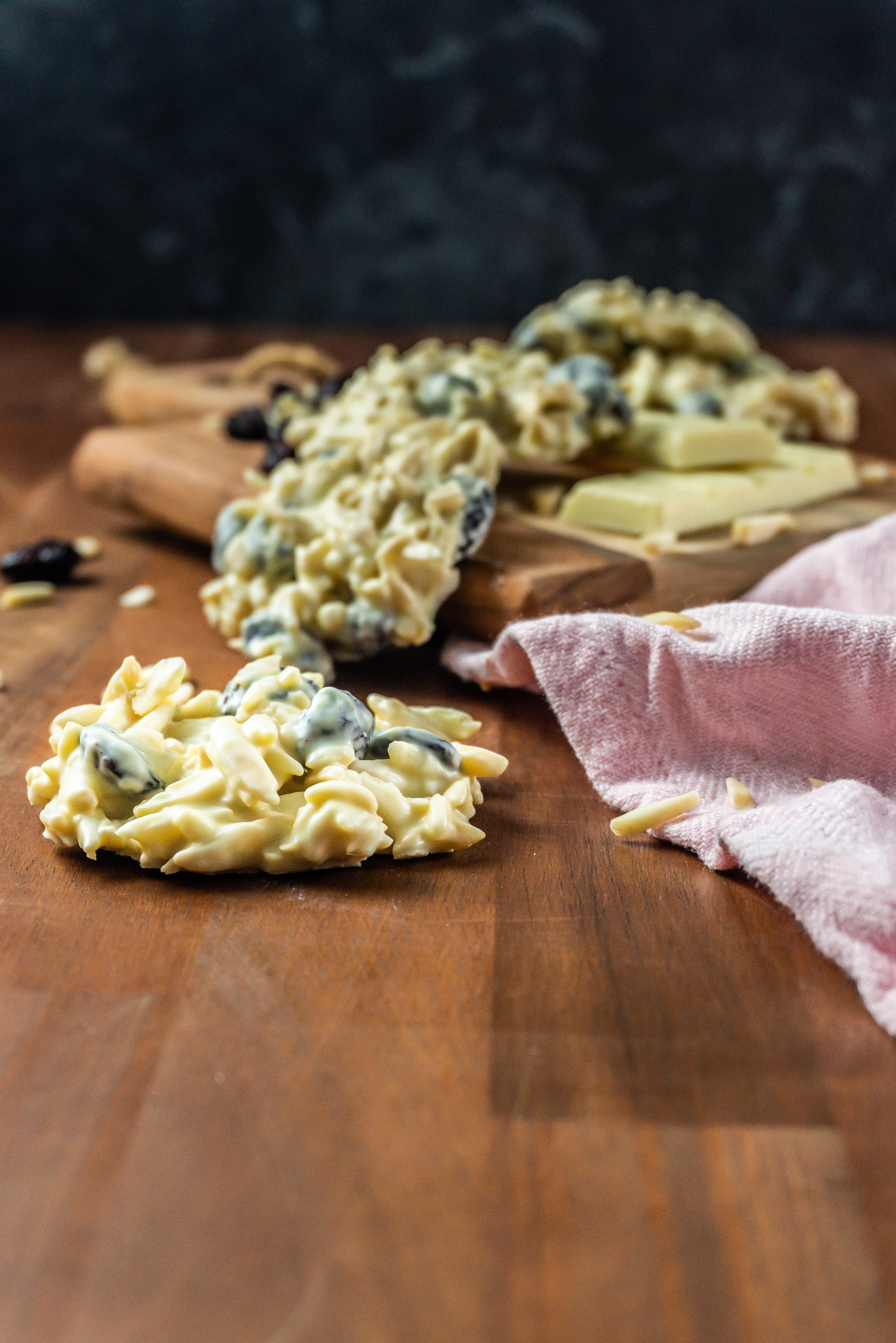 Shaved Almond and Cranberry White Chocolate Cookie in focus with more cookies scattered in the background