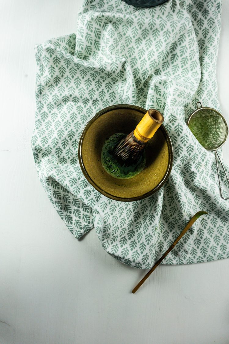 Matcha tea being made with a small whisker in a typical Japanese bowl