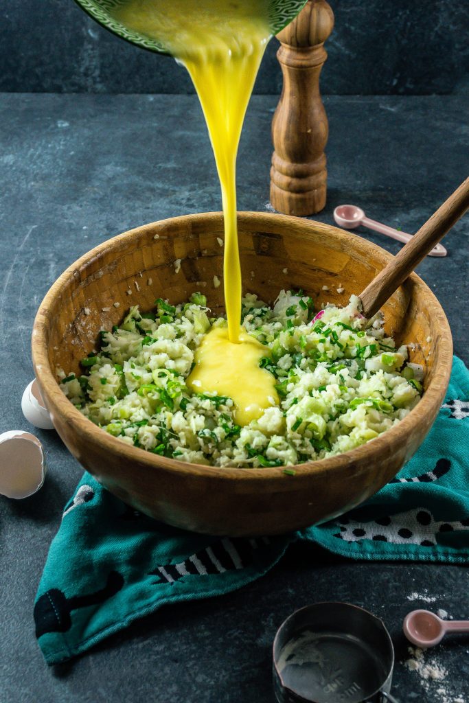 Whisked eggs are being poured into the batter for cabbage pancakes with poached eggs