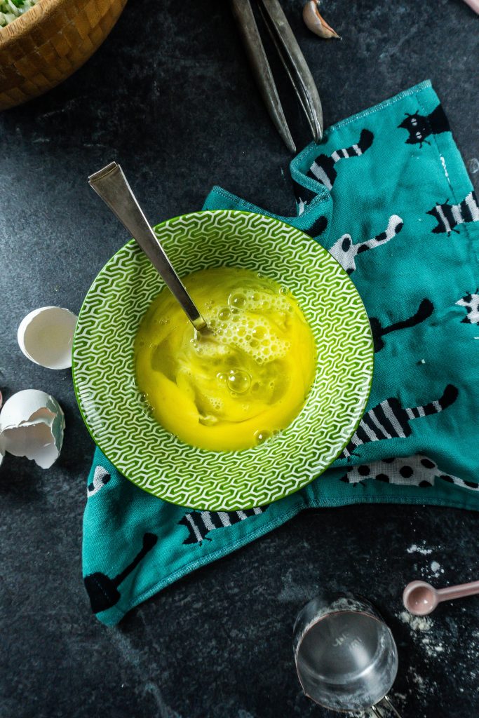 Cracked eggs in a bowl being whisked by a fork