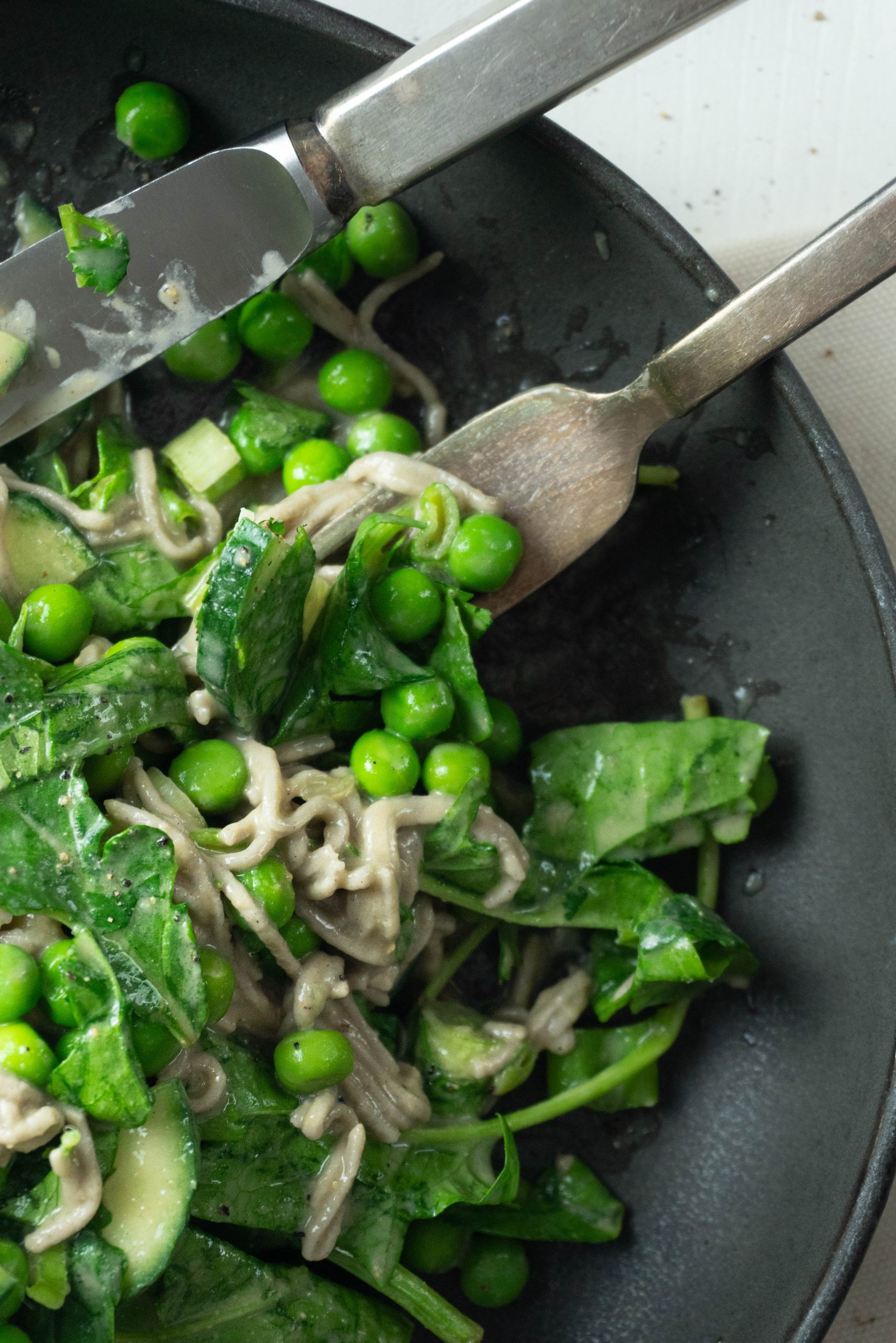 Perfect Soba Noodle Salad being picked up by a fork and knife to be eaten; photographed up close