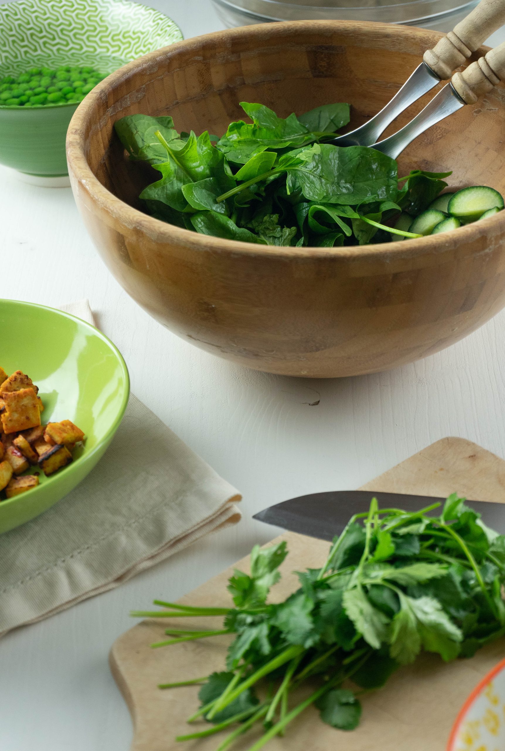 Spinach and cucumber are being prepared in a salad bowl for this Perfect Soba Noodle Salad