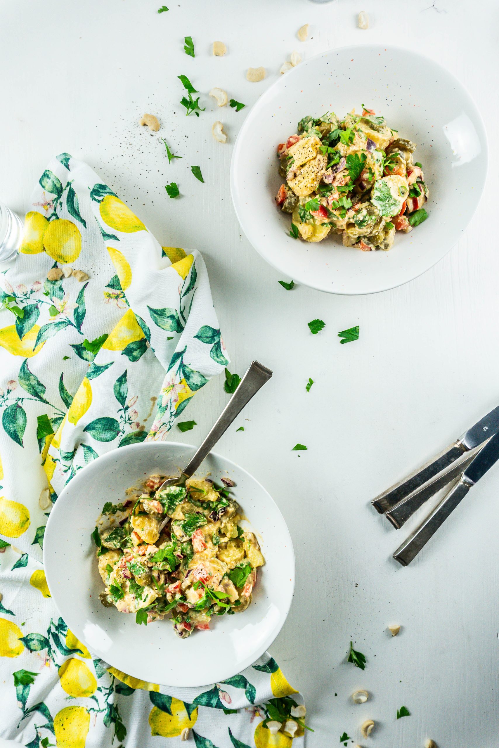 Vegan Potato Salad in two bowls, ready for serving with a fork being tugged into one of the bowls; photographed from above
