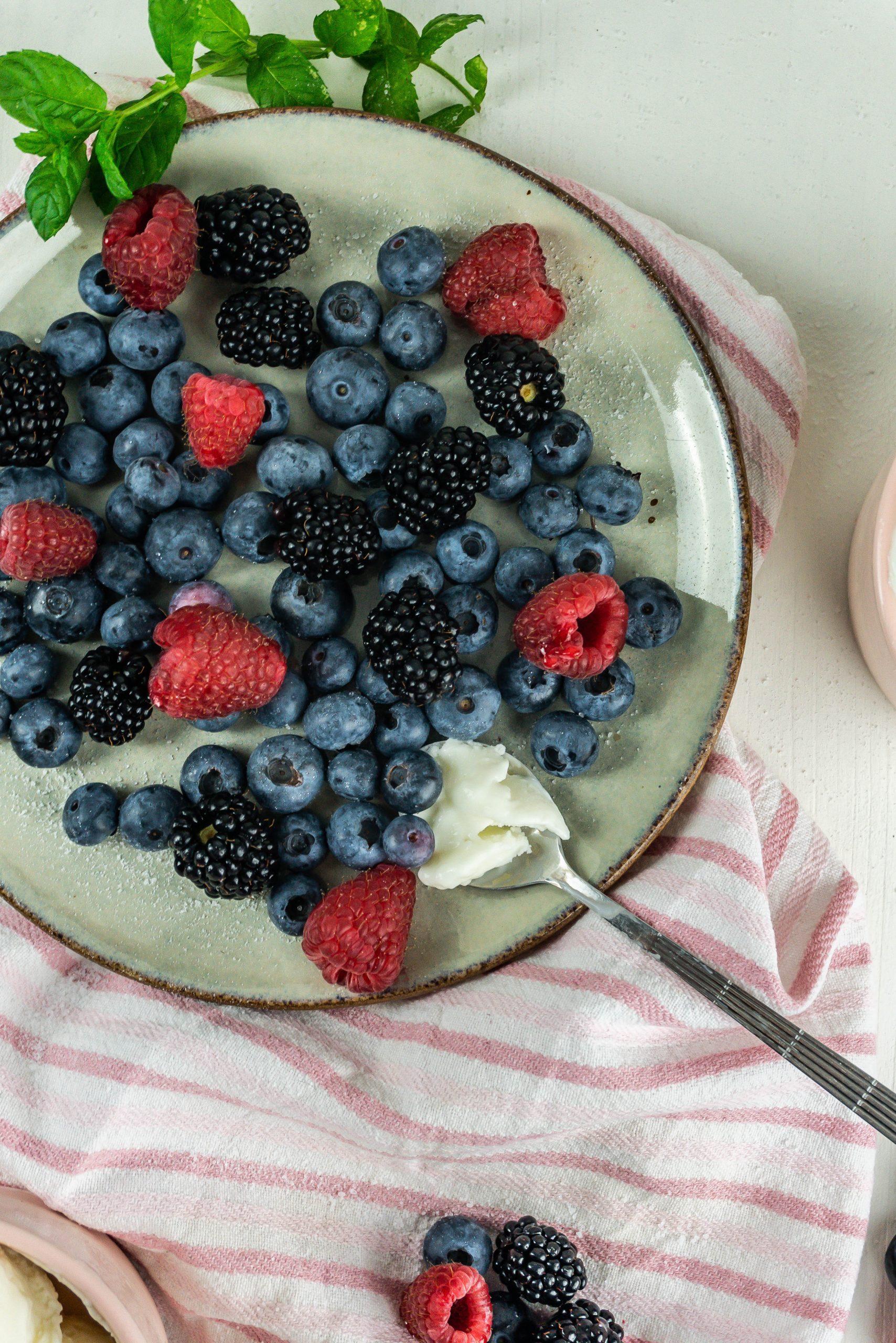 Cool and creamy yogurt ice cream on a spoon with berries on a plate