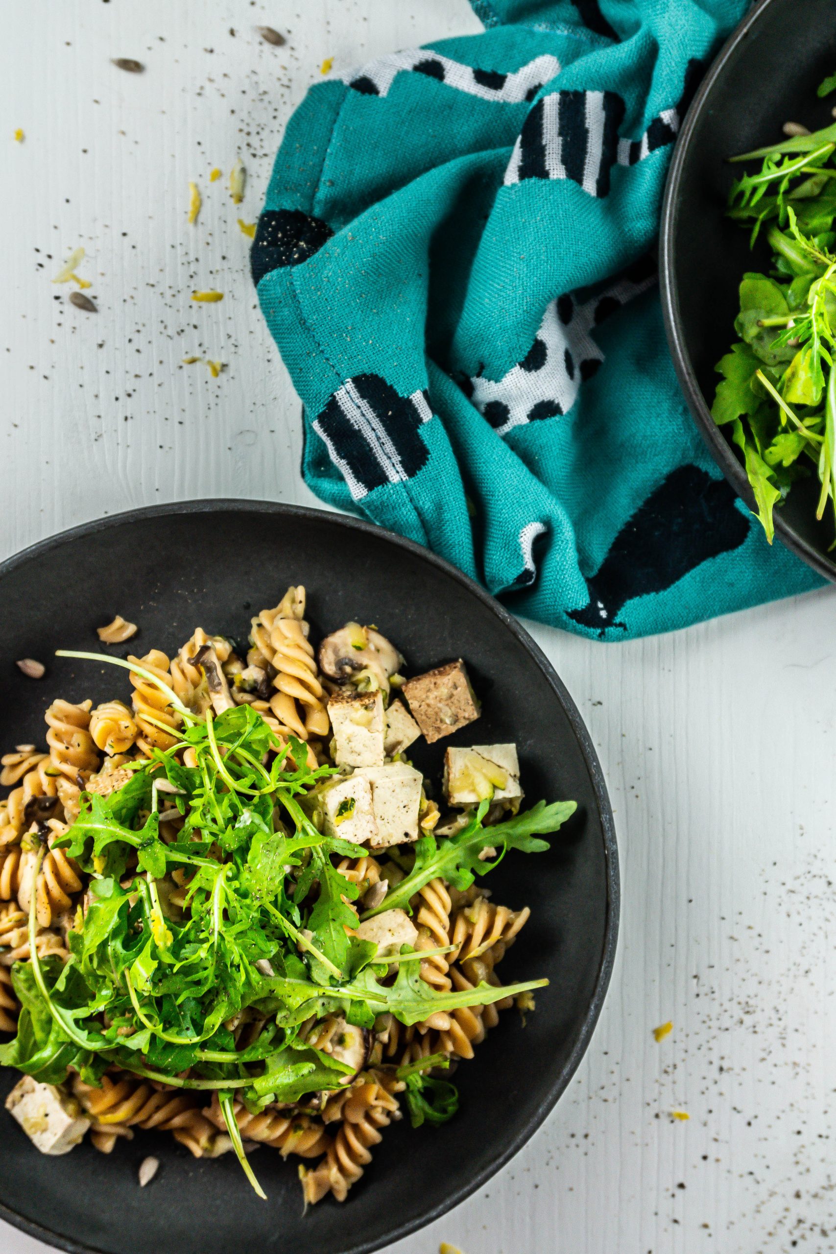 15-Minute Summer Pasta on a plate with lemon zest and arugula in the background; photographed up close