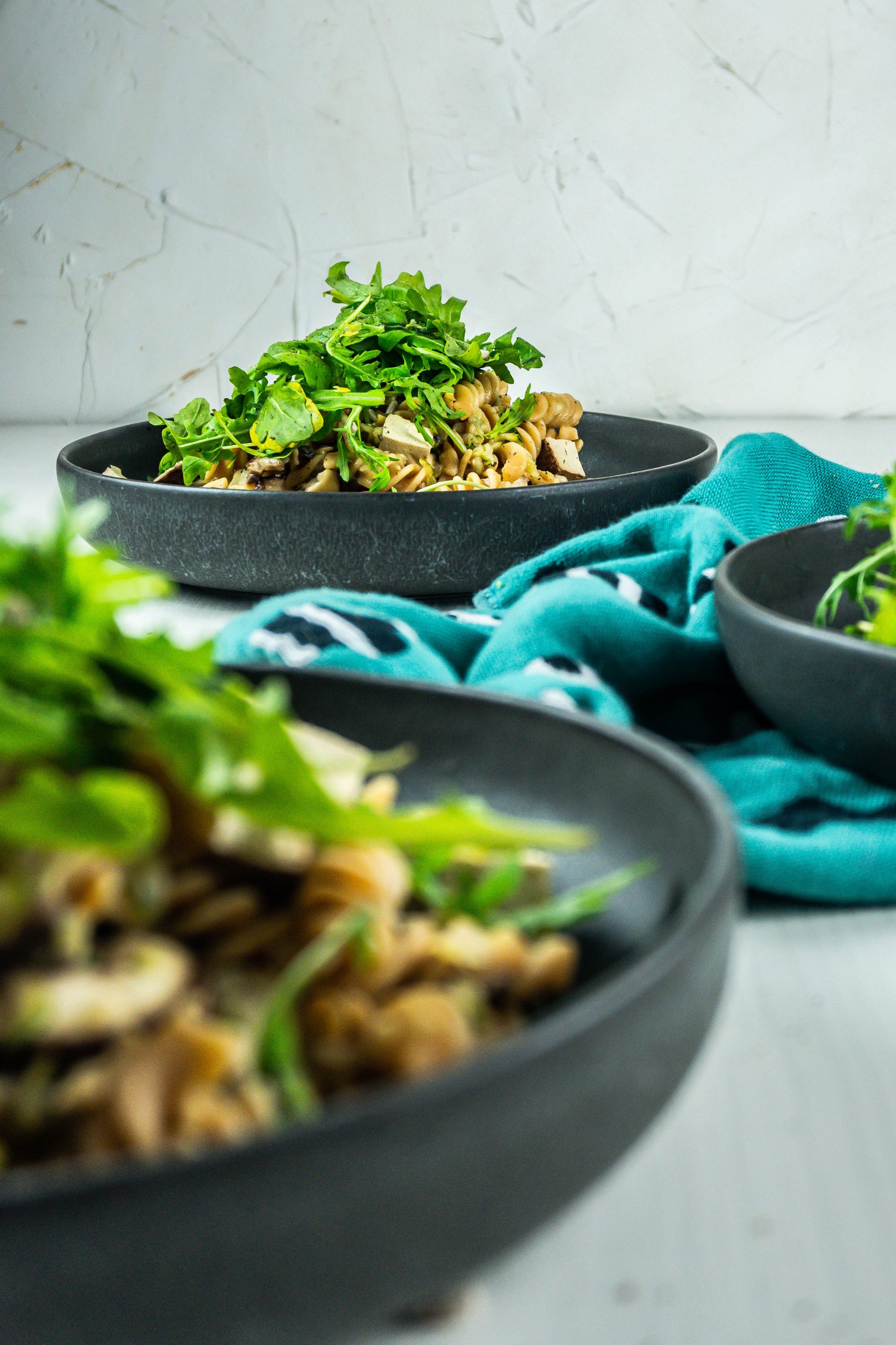 15-Minute Summer Pasta on a plate with lemon zest and arugula in the background; photographed from a three quarter angle
