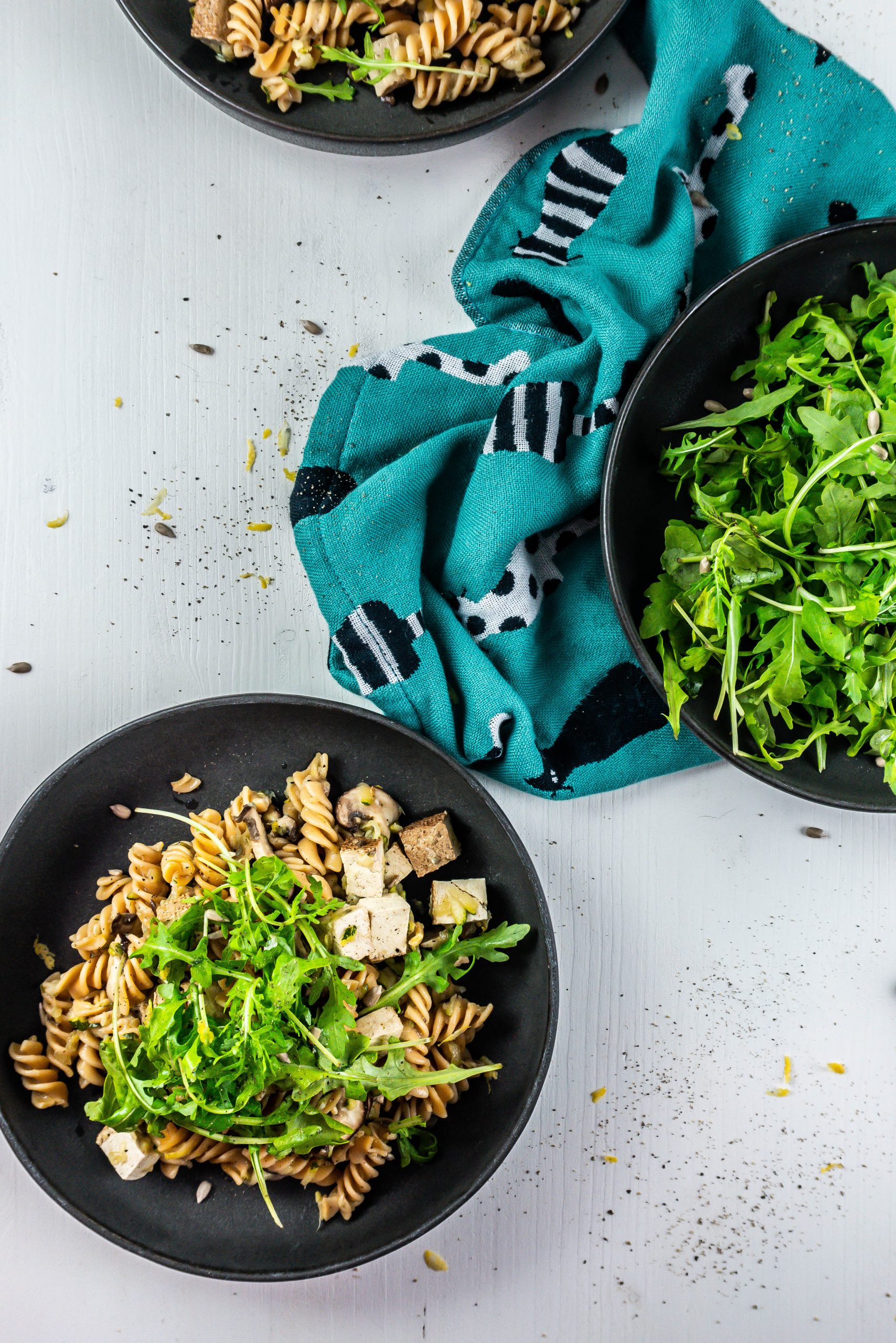 15-Minute Summer Pasta on a plate with lemon zest and arugula in the background; photographed from above