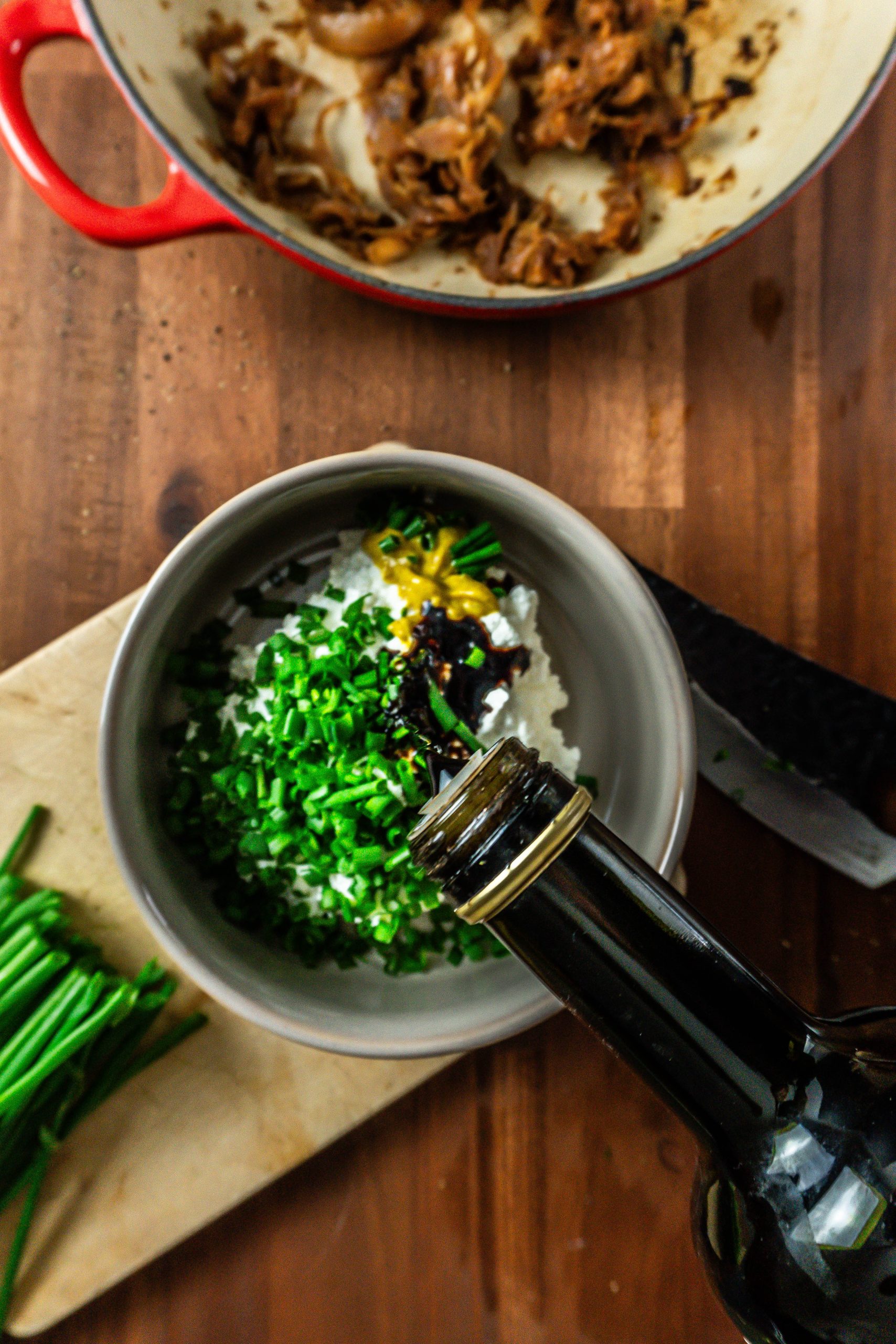Balsamic vinegar being in focus and being added to the crowd-pleasing caramelized onions dip