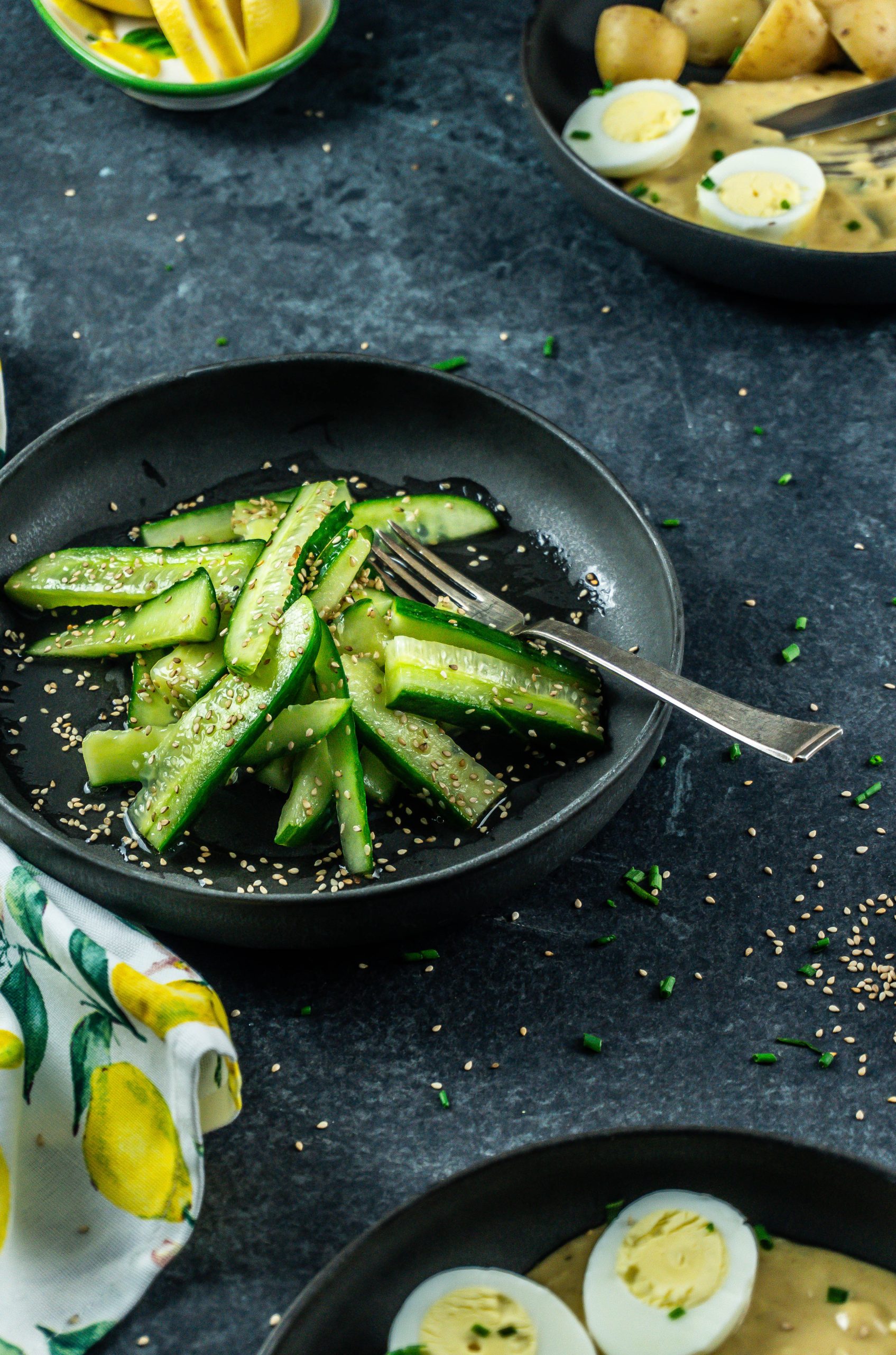 Japanese-Inspired Cucumber Salad with a fork on the plate and sesame seeds scattered in the background; photographed from a side-angle