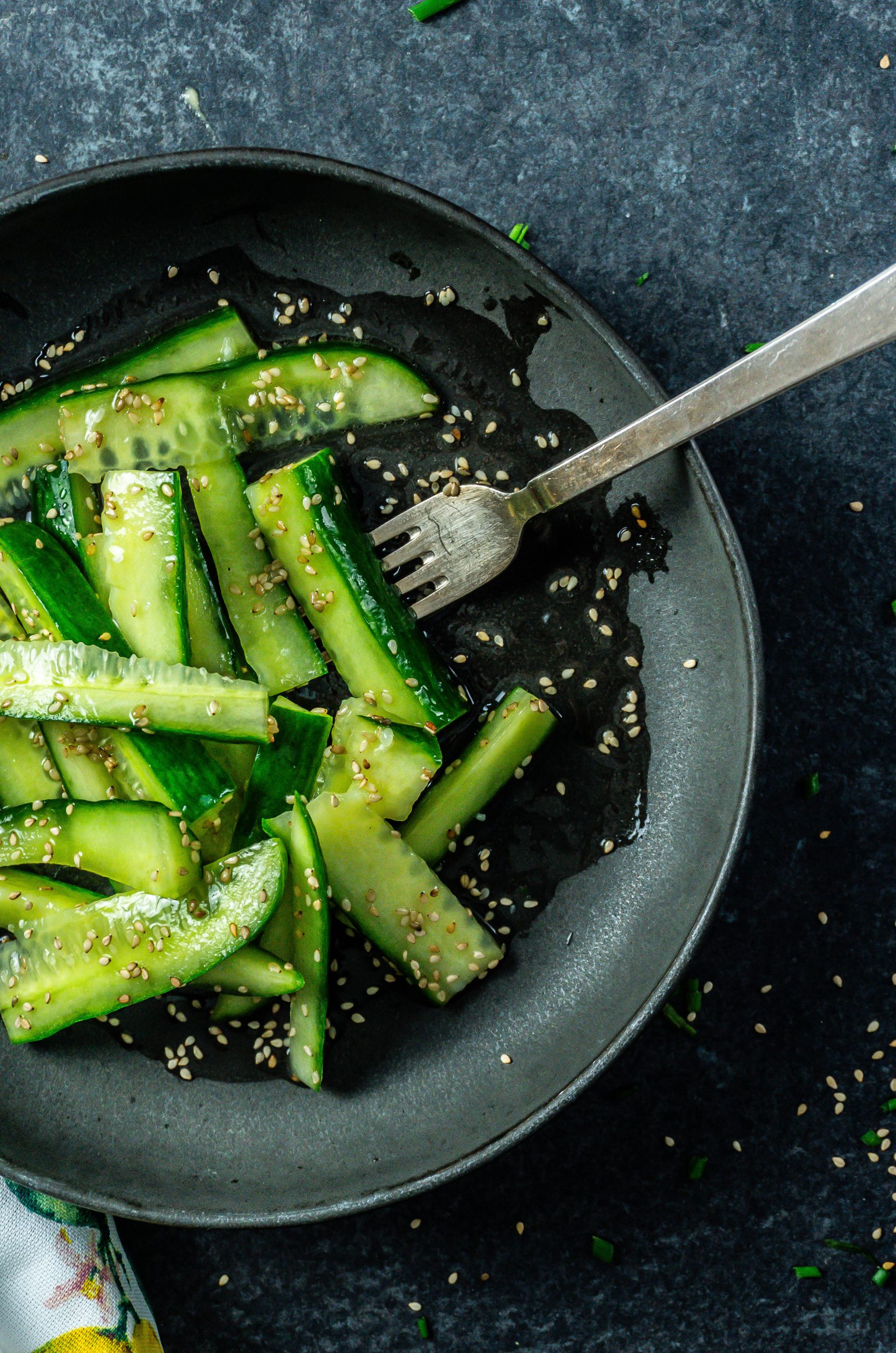 A fork tugging into a Japanese-Inspired Cucumber Salad; photographed from above