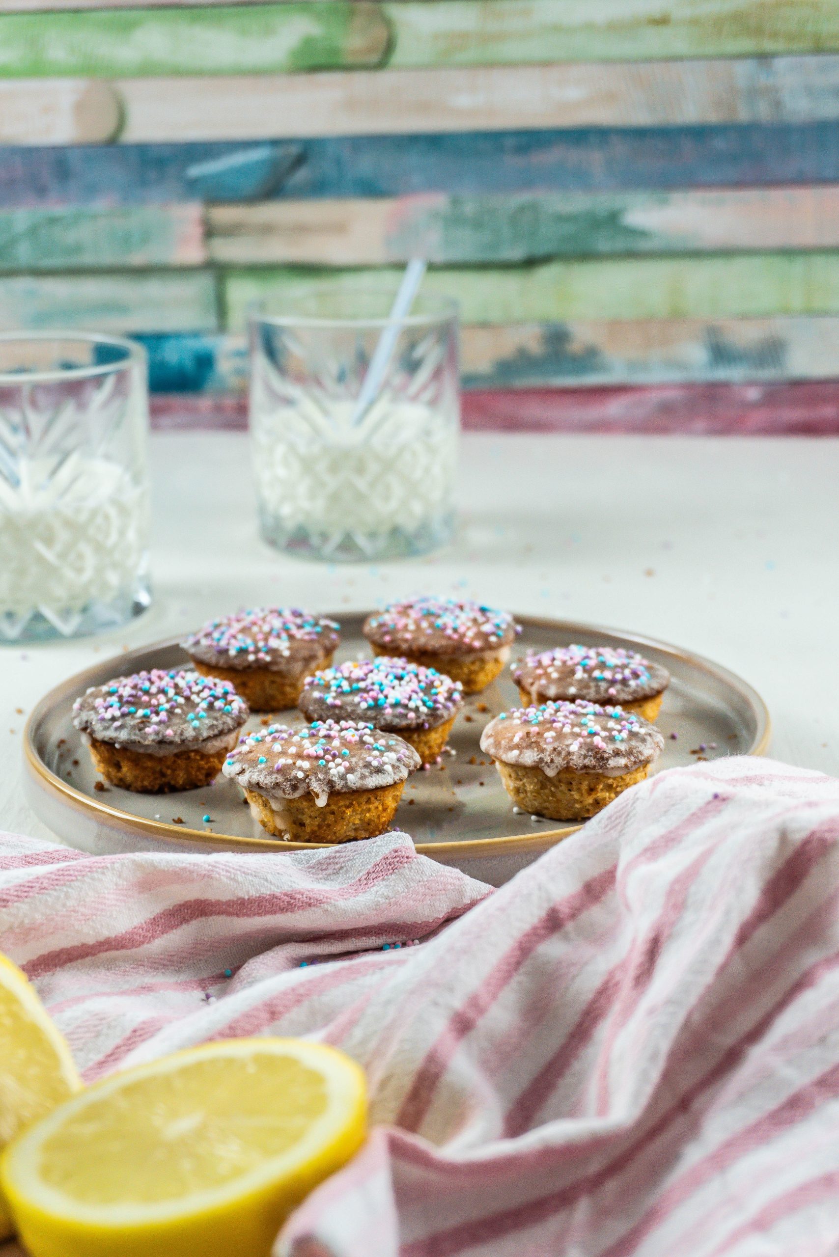 Lemon Mascarpone Mini Muffins on a small plate with two glasses of milk in the background and some sprinkles surrounding the plate