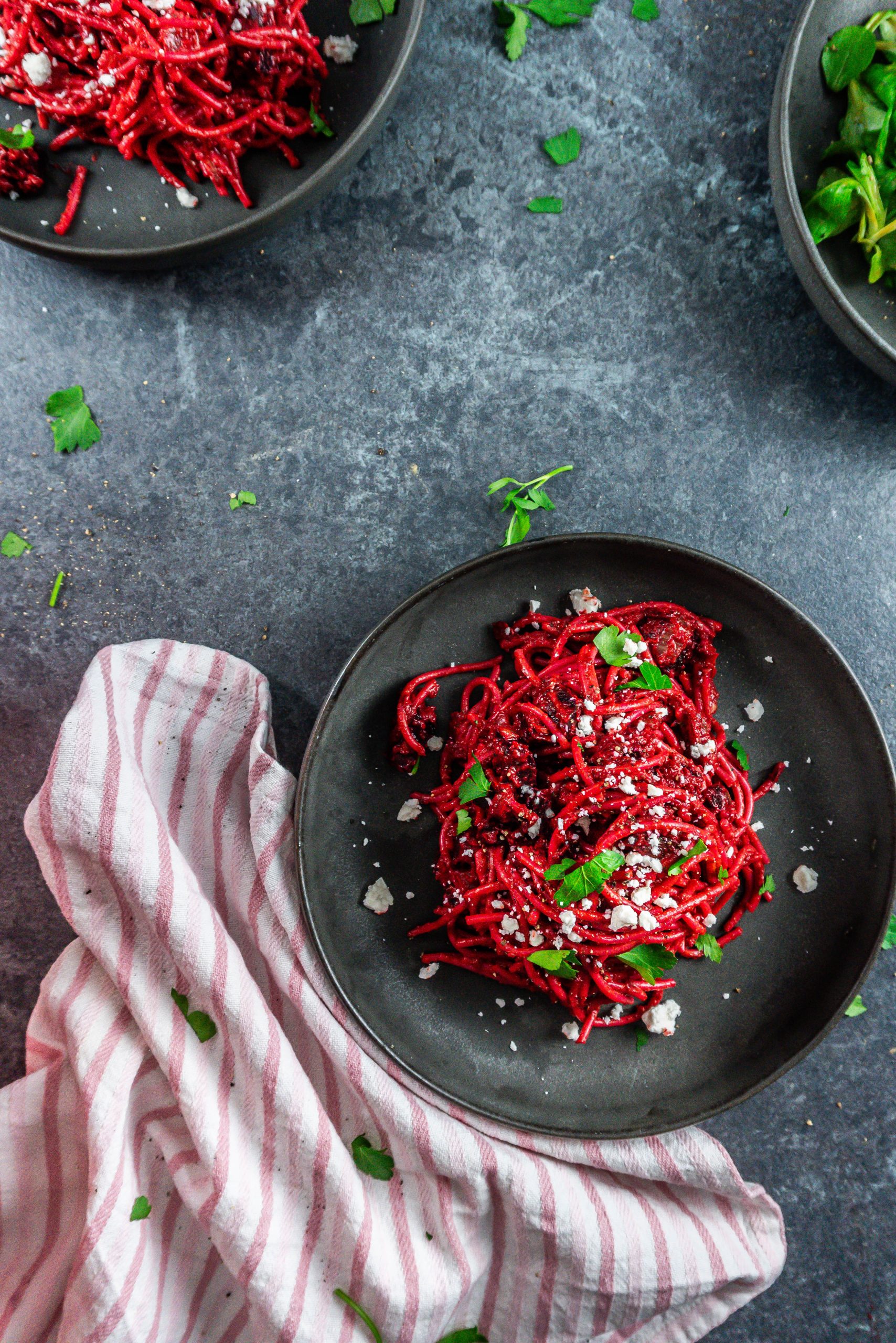 Creamy Blender Beetroot Pasta on a dark plate with crumbled feta cheese and chopped parsley on top; photographed fro m above