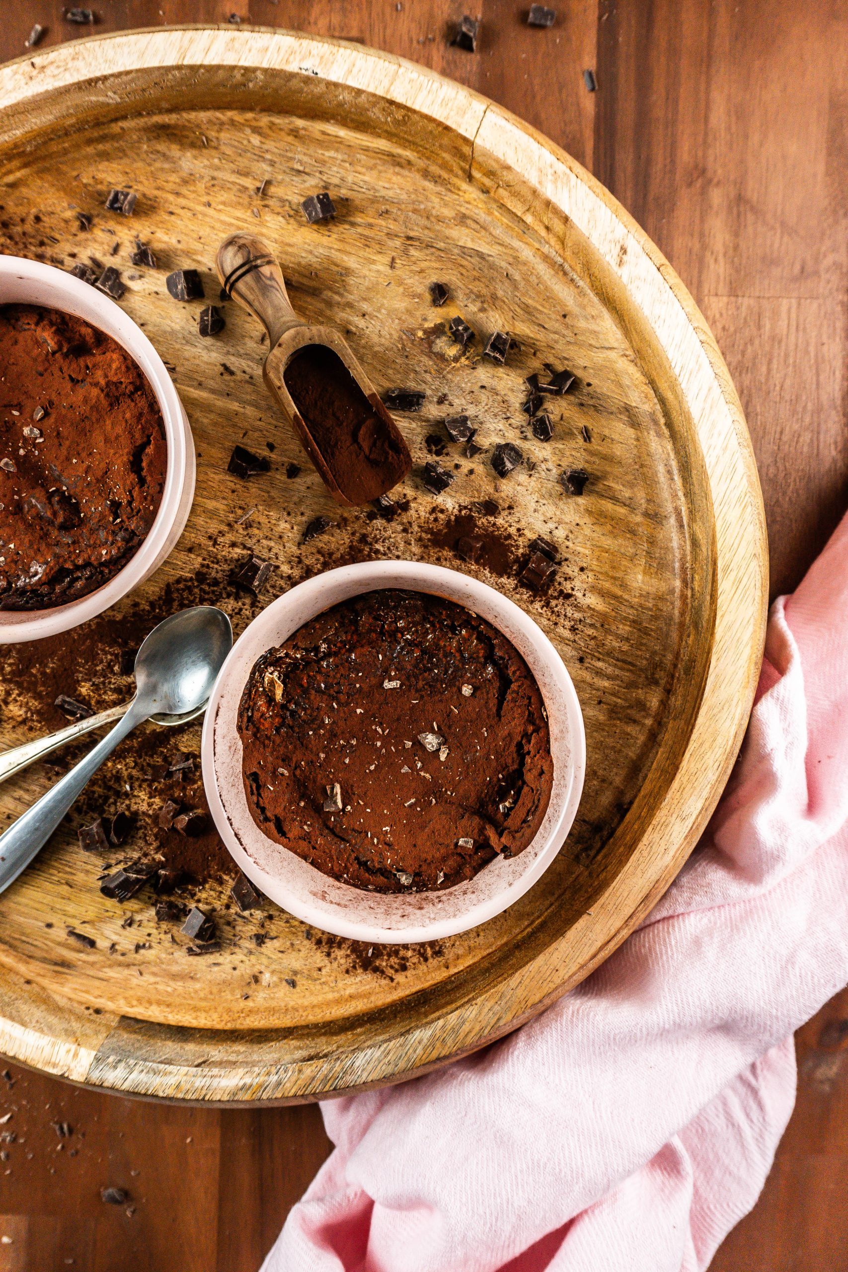 Gluten-free warm, fudgy mug brownie in in an oven-proof ramekin surrounded with chopped chocolate and cocoa powder