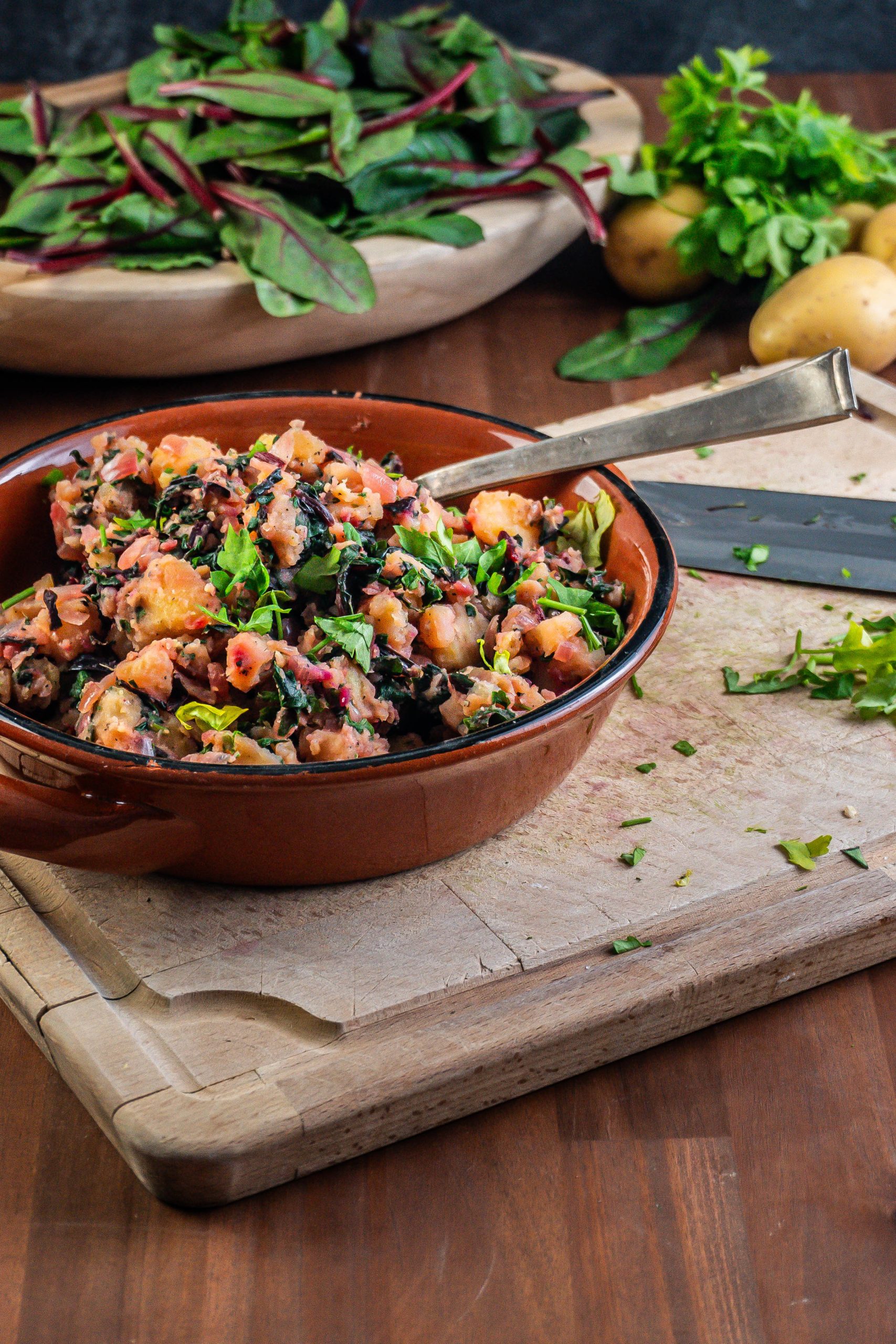 Blitva - Croatian Swiss Chard and Potatoes in a brown bowl with a spoon stuck into it