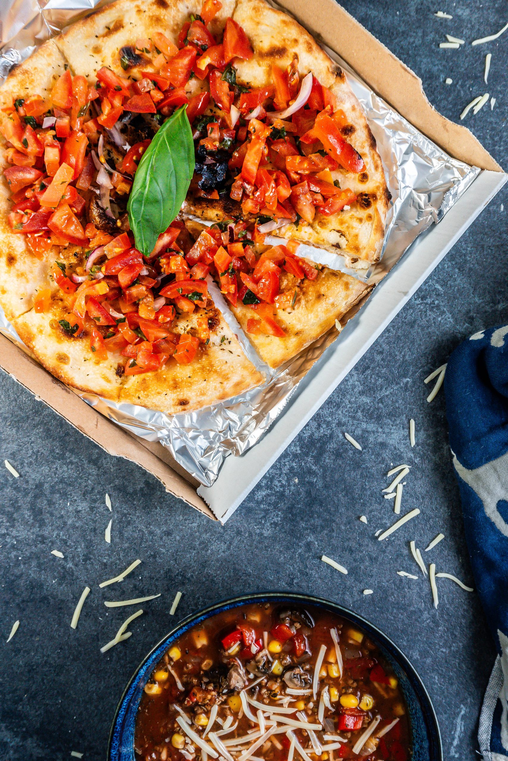 Pizza bread visible in focus with tomatoes and onions on top