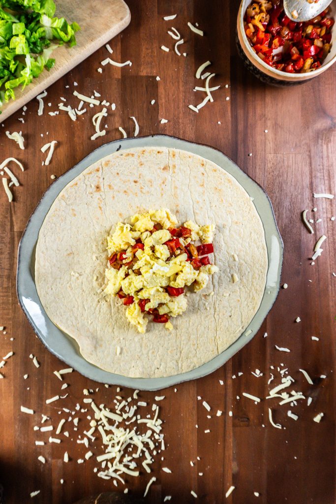 Wrap with fried onion and red peppers and scrambled eggs surrounded by other ingredients for the 15-Minute Vegetarian Lunch Crunch Wrap