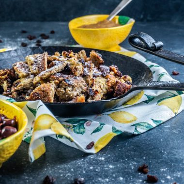 Gluten-free Kaiserschmarrn in a cast iron pan with some dusted xylitol on top and some apple sauce in the back; photographed from a side-angle