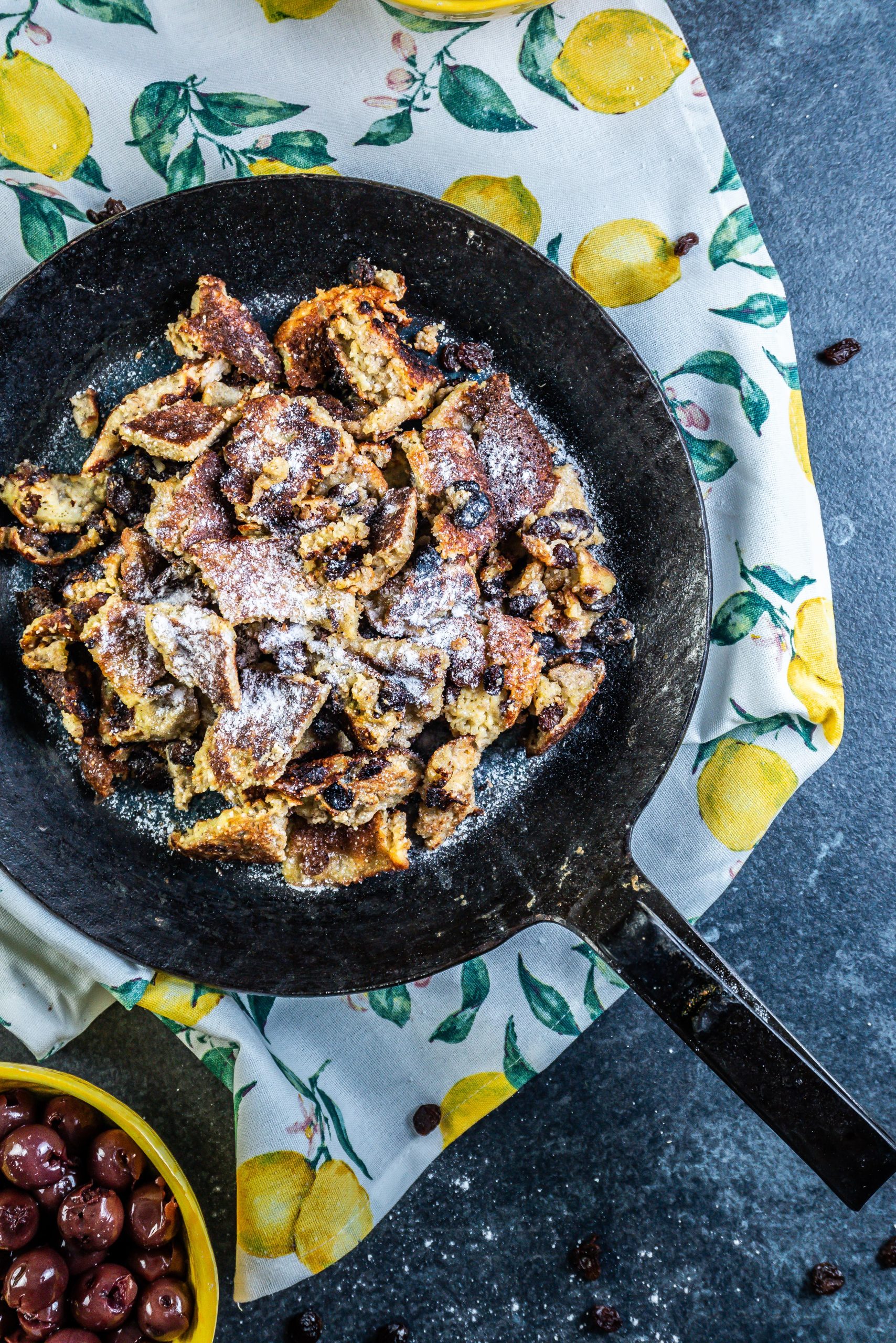 Gluten-free Kaiserschmarrn in a cast iron with some powdered xylitol on top and some cherries to go with on the side; photographed from the top