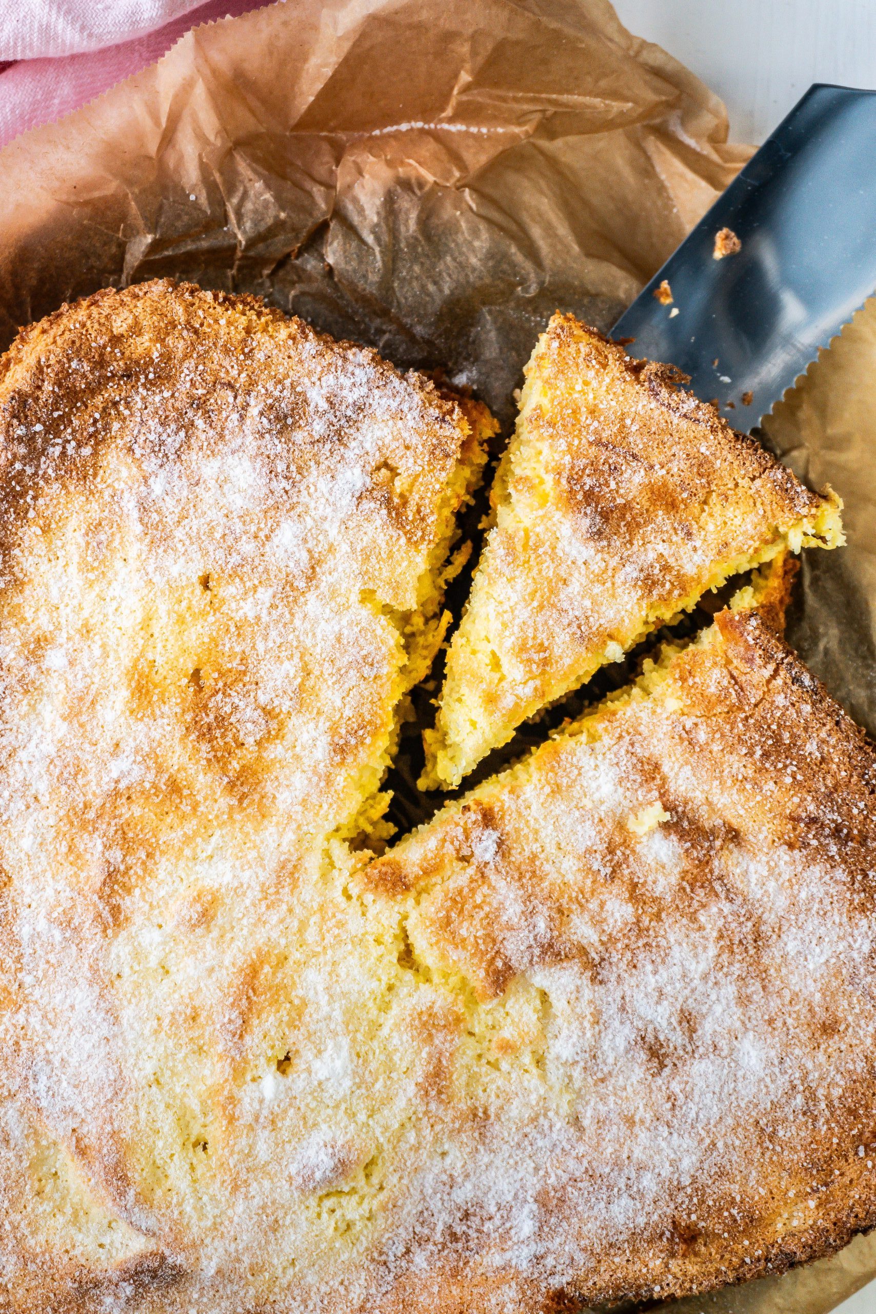 A piece of polenta pound cake is being taken out of the overall take; photographed up close