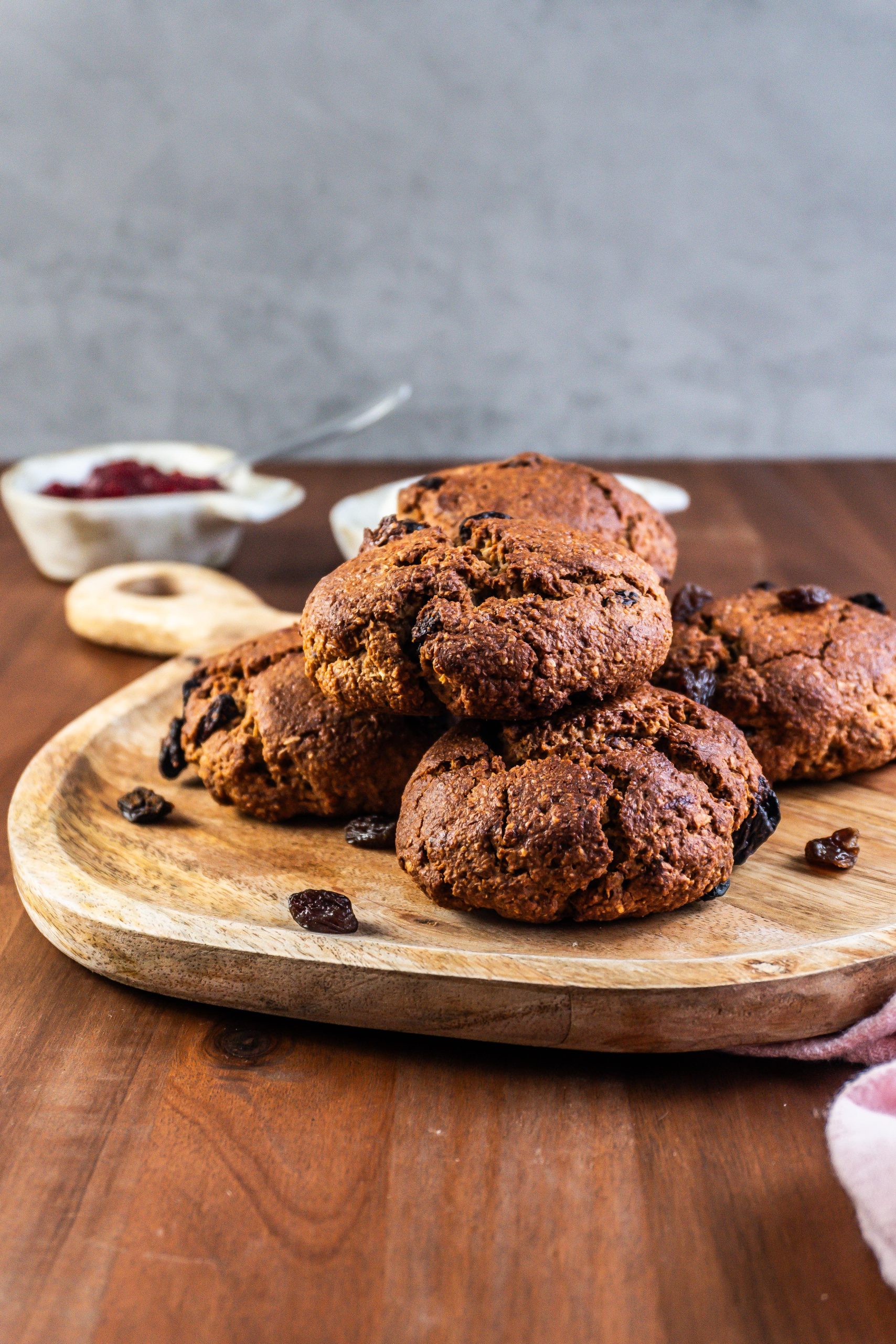 Cinnamon Orange Raisin Scones arranged on a platter with some jam and yogurt visible to the side; photographed from a side angle