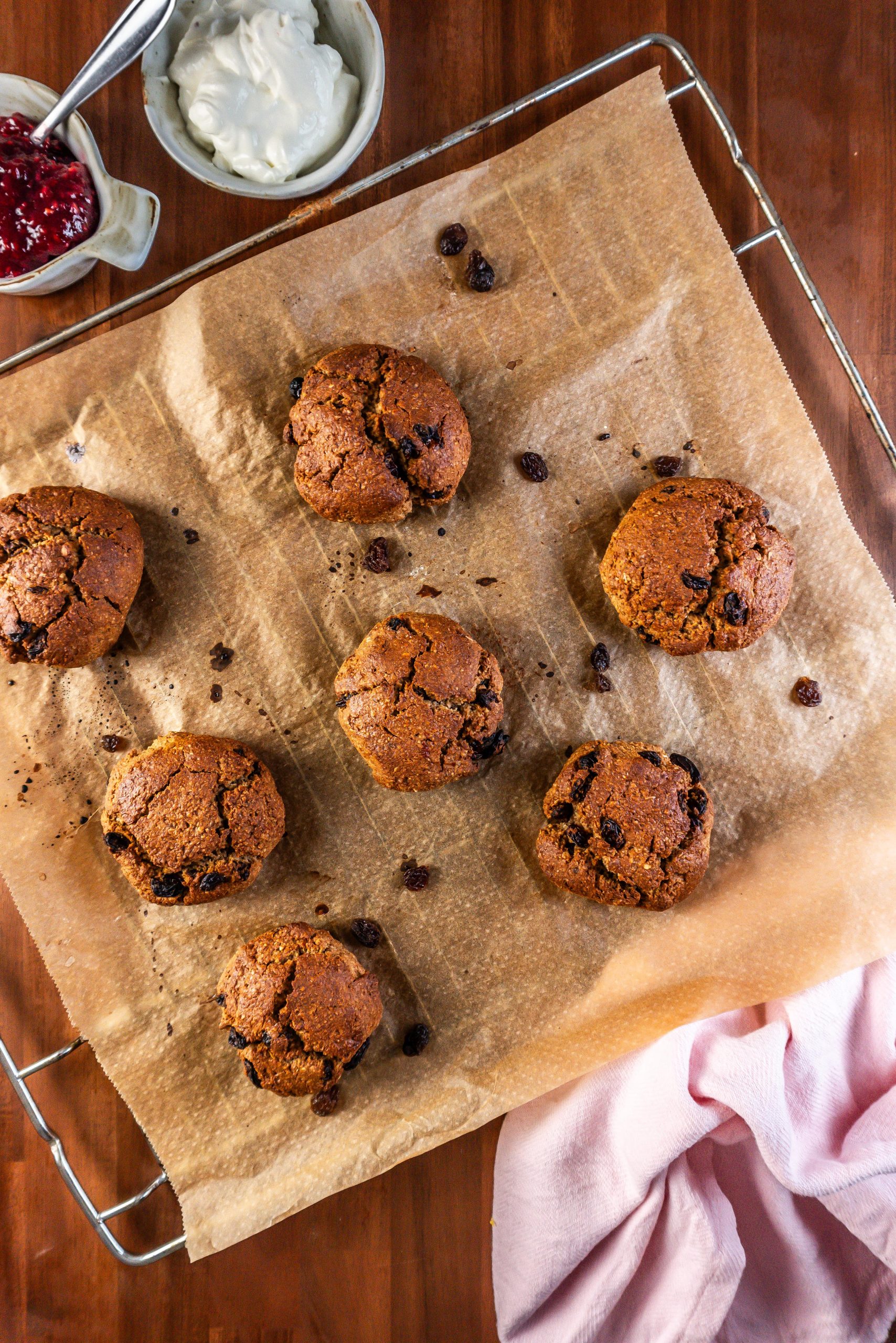 Cinnamon Orange Raisin Scones on a baking tray with some jam and yogurt visible in the background