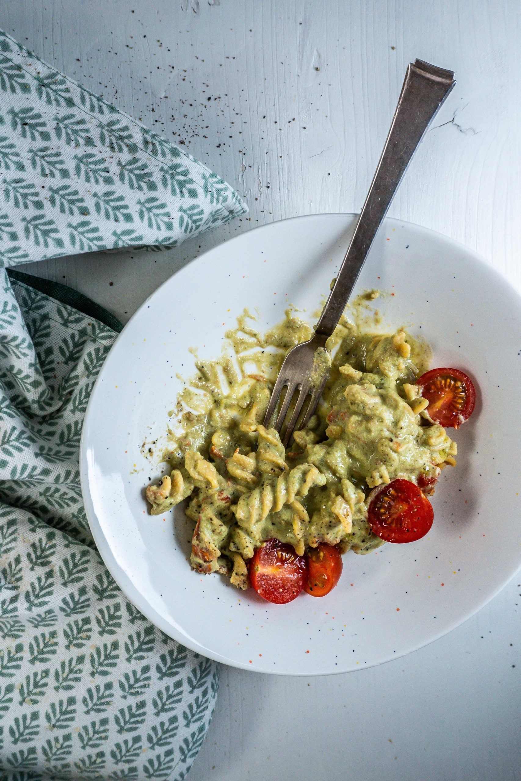 Creamy Avocado Pasta Recipe plated in a bowl with a fork stuck in and the pasta being half eaten
