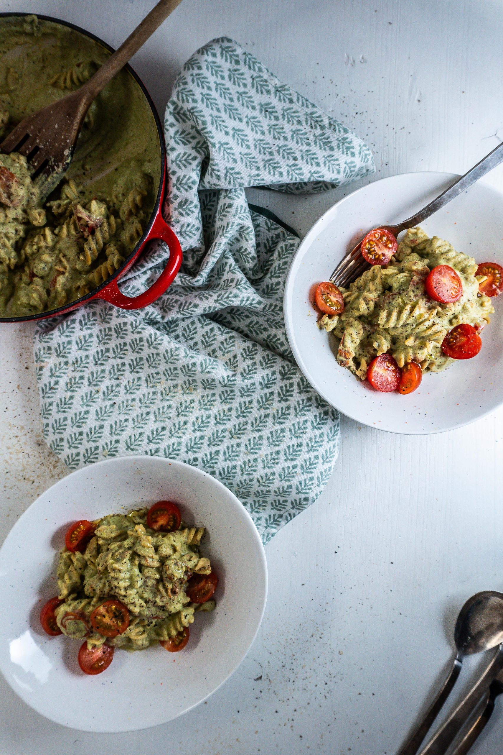Creamy Avocado Pasta Recipe plated in two bowls with a fork stuck into one, with the casserole dish that the pasta was made in visible to the side