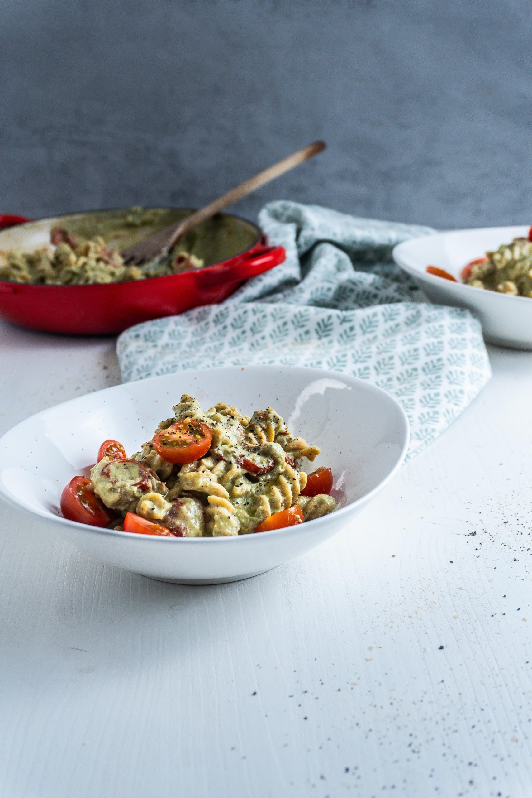 Creamy Avocado Pasta Recipe in a bowl, highlighted with the casserole dish in which it was made visible in the background