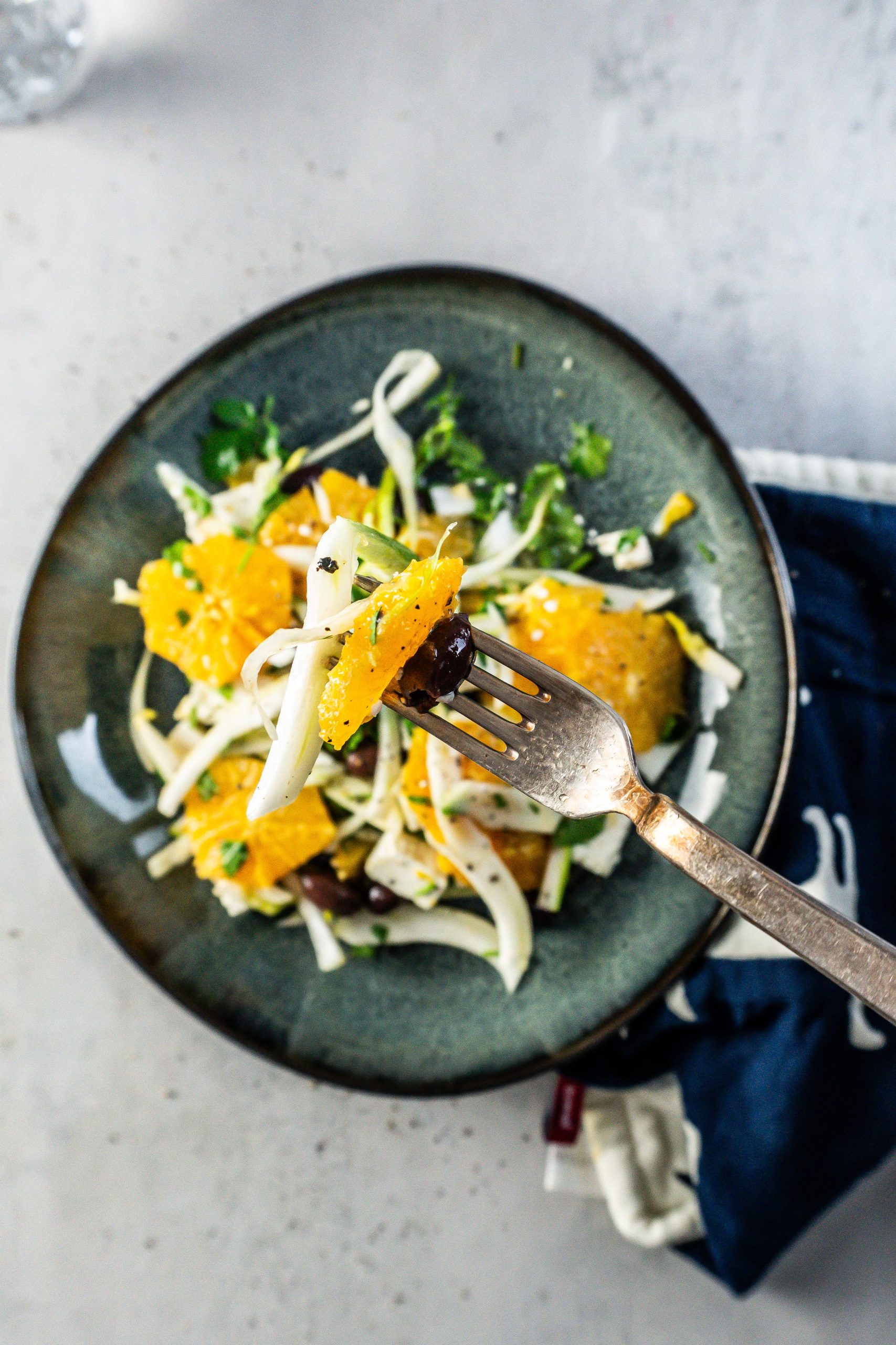 Mediterranean Fennel and Orange Salad on a fork with the plate of food visible in the background