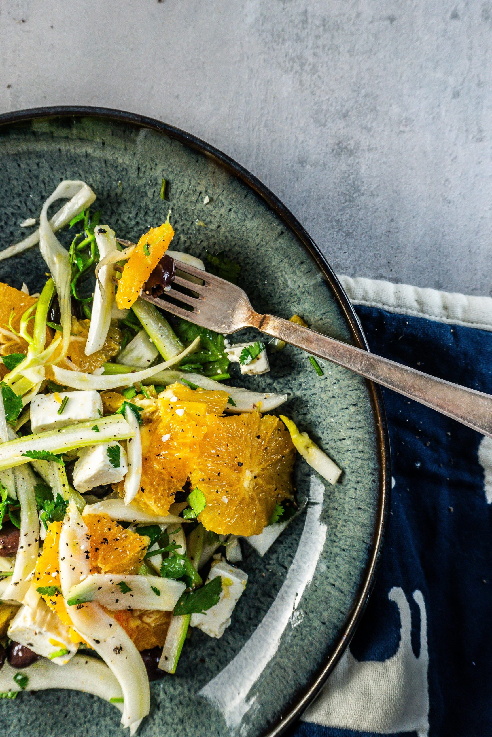 Mediterranean Fennel and Orange Salad on a dark plate with some of the salad being picked up on the fork