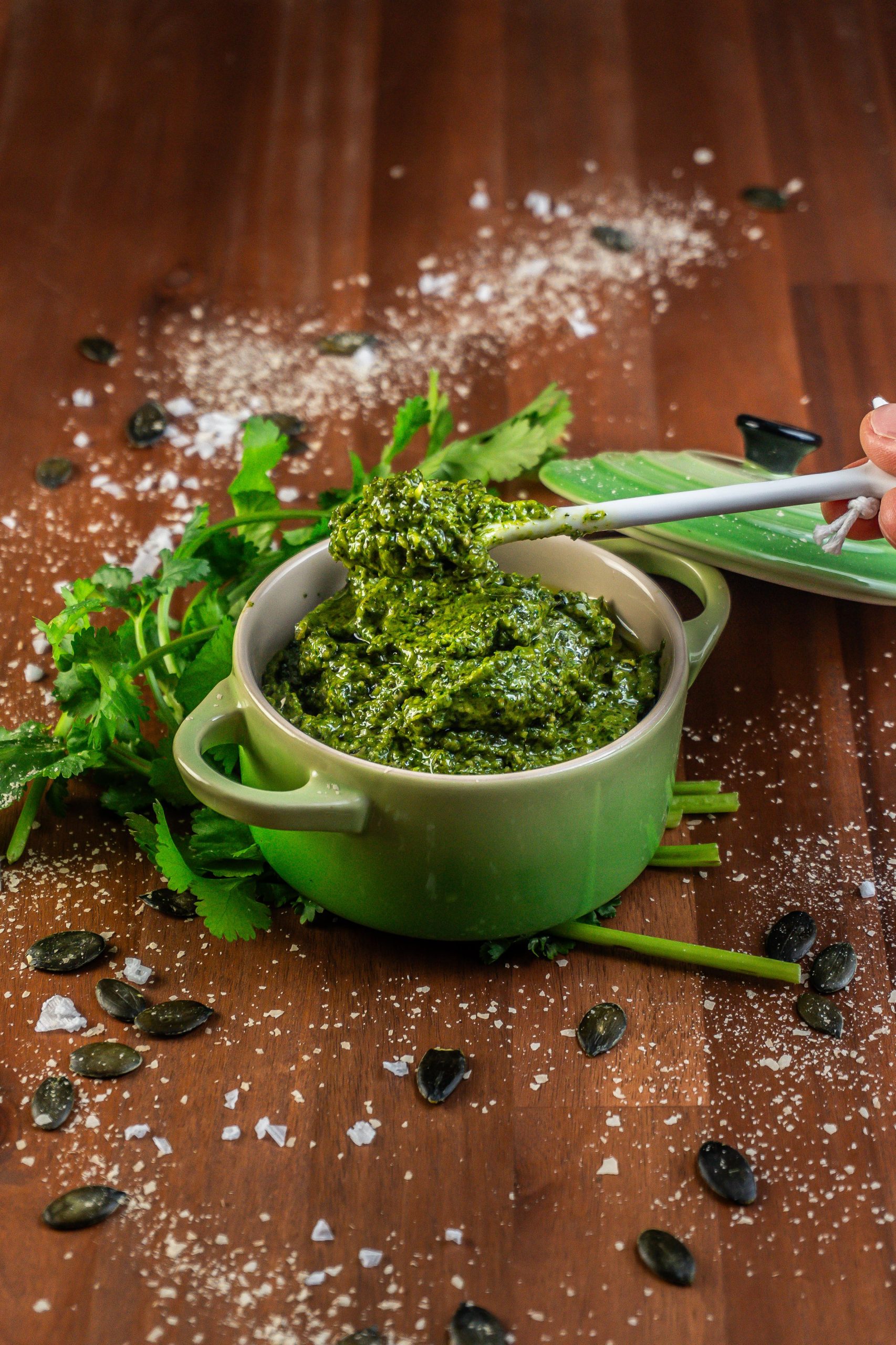 Five Minute Vegan Pepita Cilantro Pesto being lifted on a spoon from a small ramekin dish