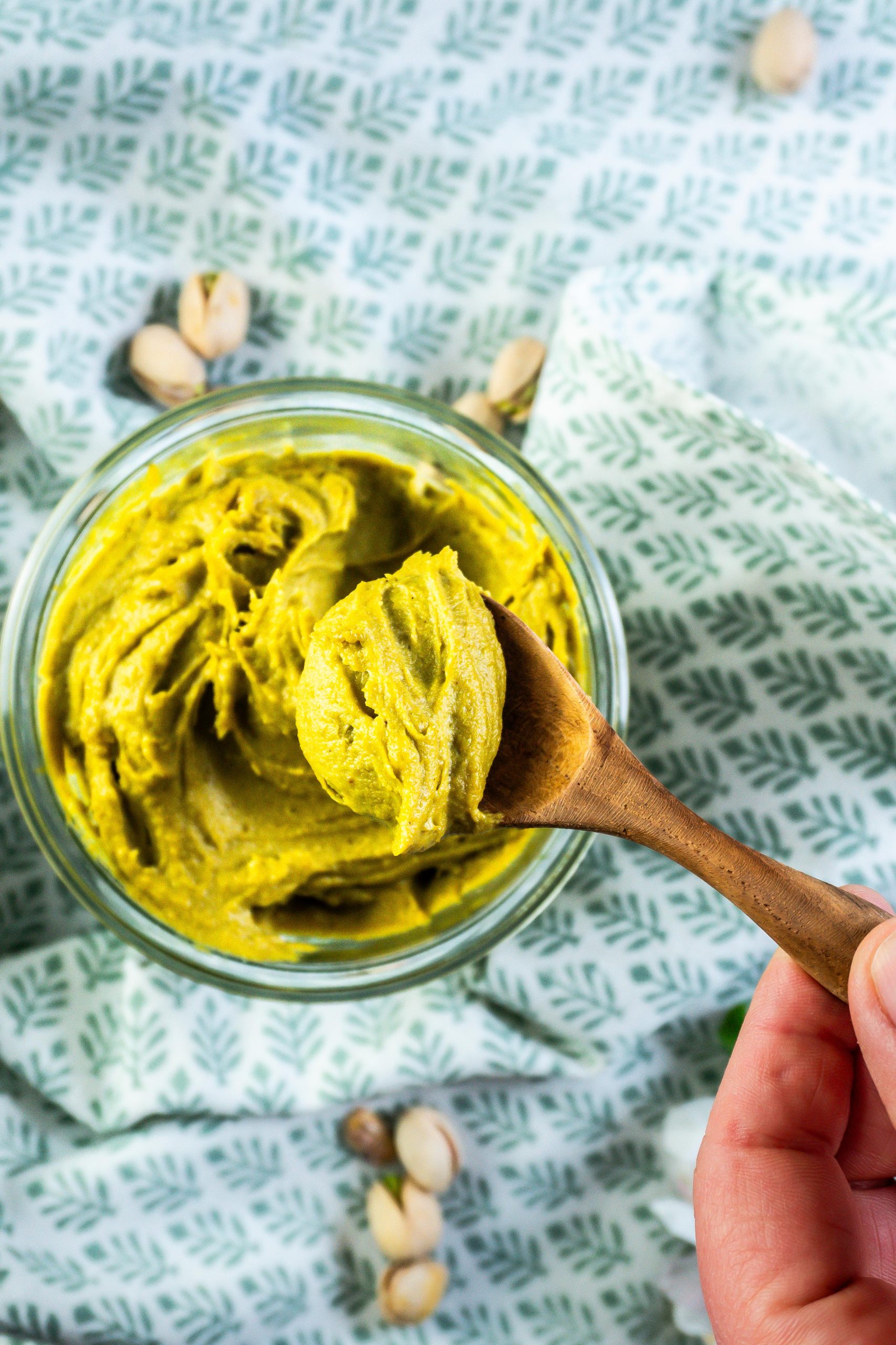 Pistachio nut butter on a wooden spoon photographed up close