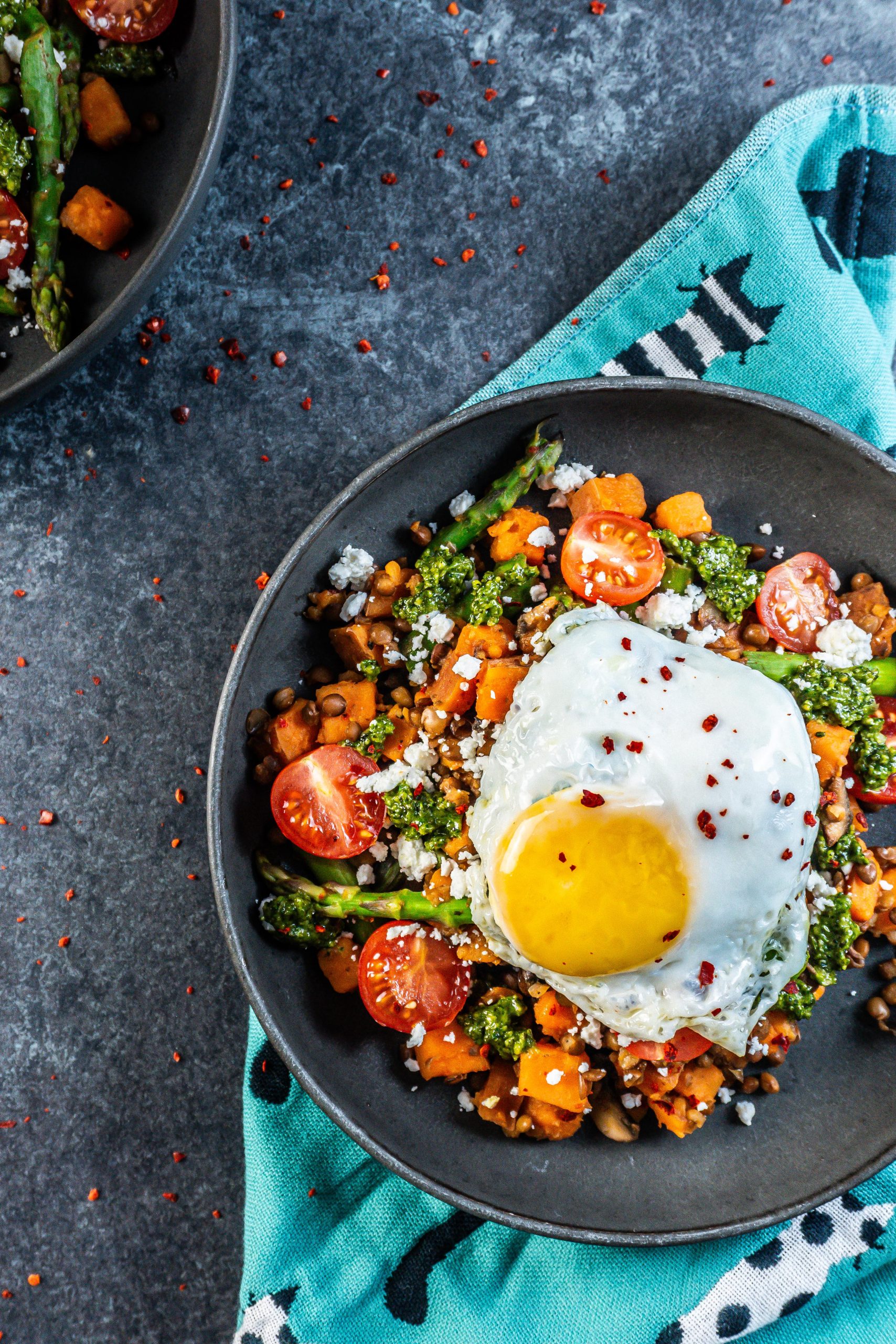 Savory Breakfast Bowl with a sunny upside egg plated in a dark bowl and some chili flakes scattered around