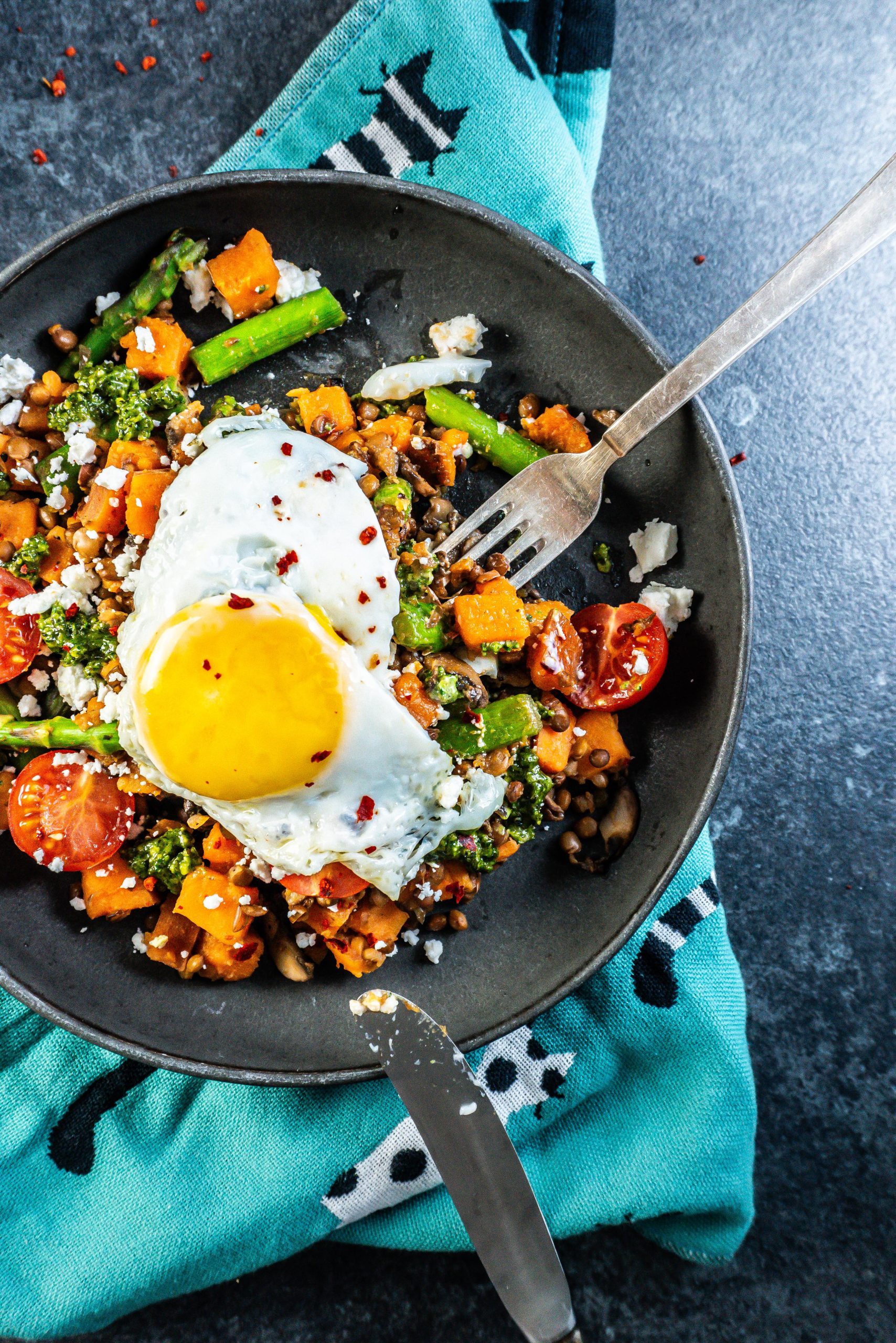 Savory Breakfast Bowl being half eaten with a knife and fork tugging into it; photographed from above