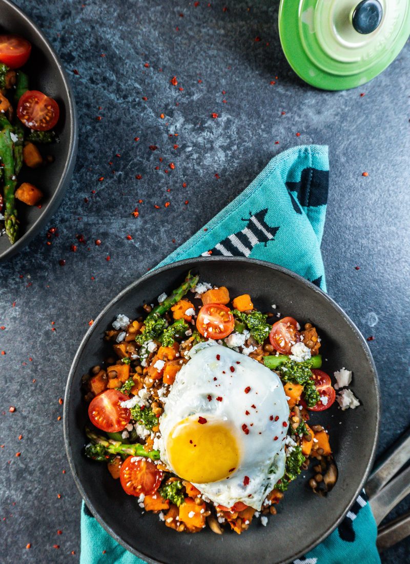 Savory Breakfast Bowl with a sunny upside egg plated in a dark bowl and some chili flakes scattered around; photographed from above