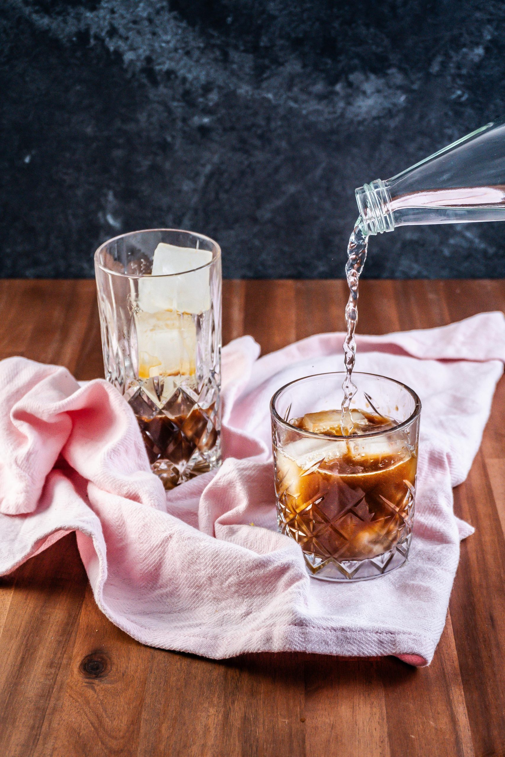 Coffee Ginger Elixir in the making with coffee, ginger, and maple syrup already in the glass with mineral water being added