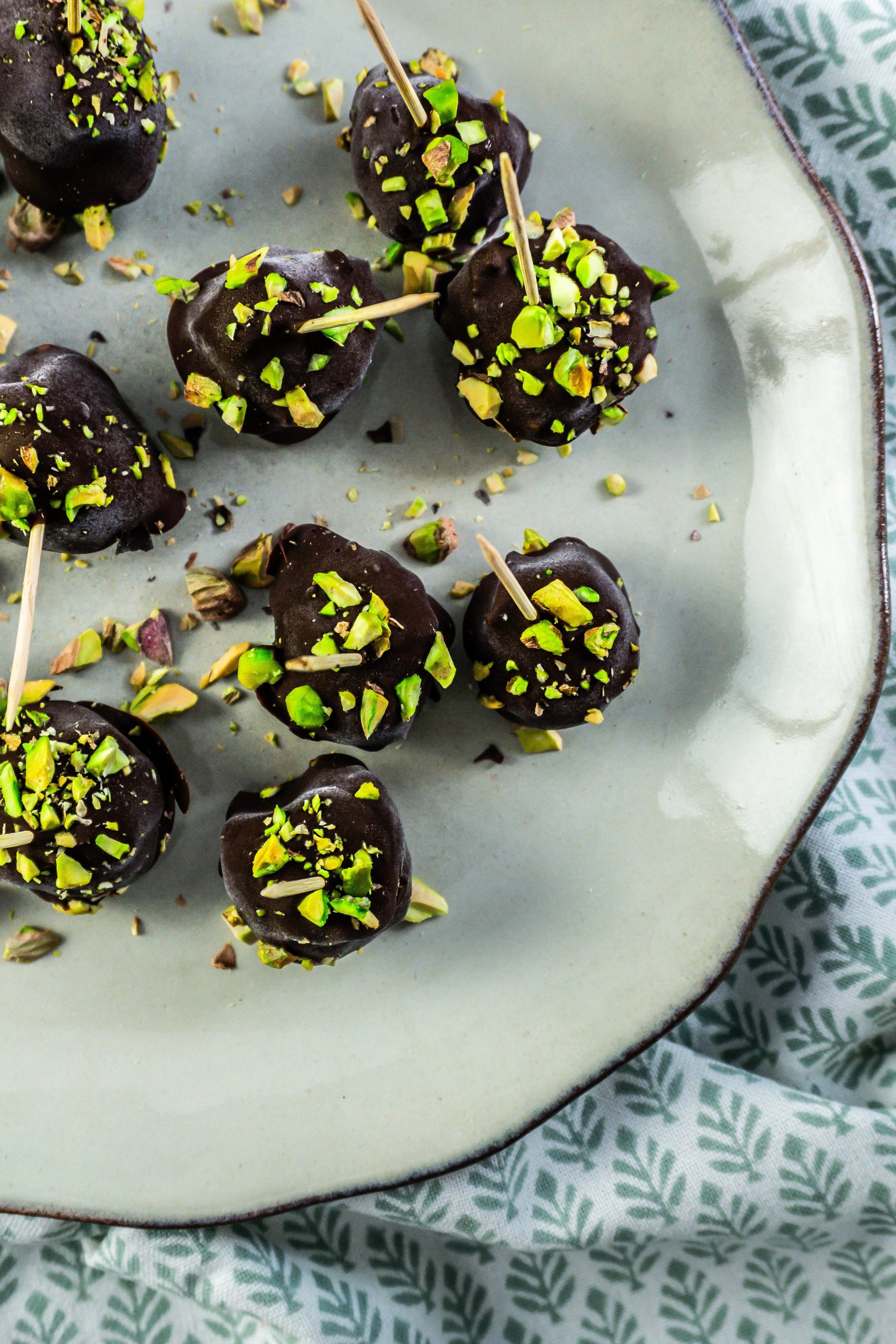 Gluten-free Dubai Style Pistachio Balls on a plate with some chopped pistachios strewn on top; photographed up close and from above
