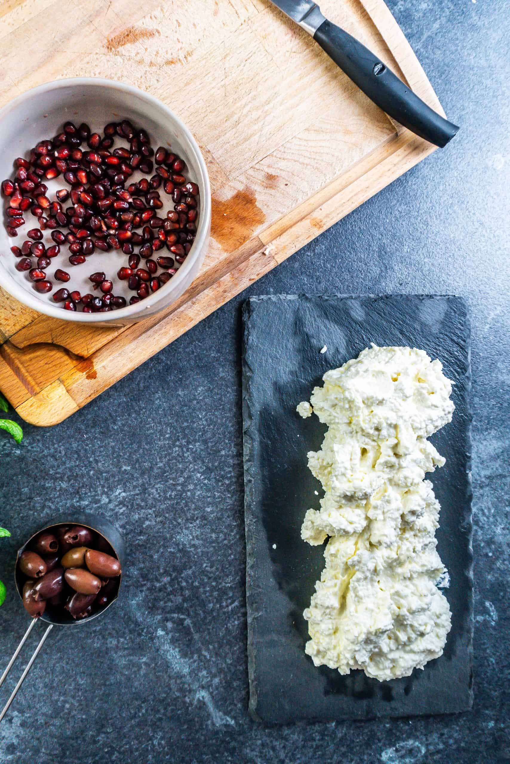 Cottage cheese and feta mixed together on a serving platter, surrounded by other ingredients