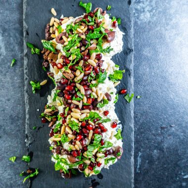 Creamy whipped feta dip on a serving plate with mint leaves strewn across the top