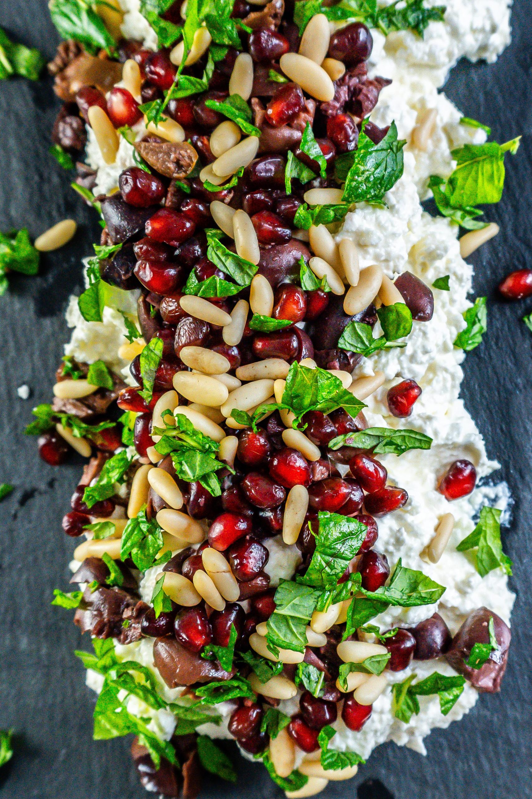 Creamy whipped feta dip on a serving plate with mint leaves strewn across the top; photographed up close