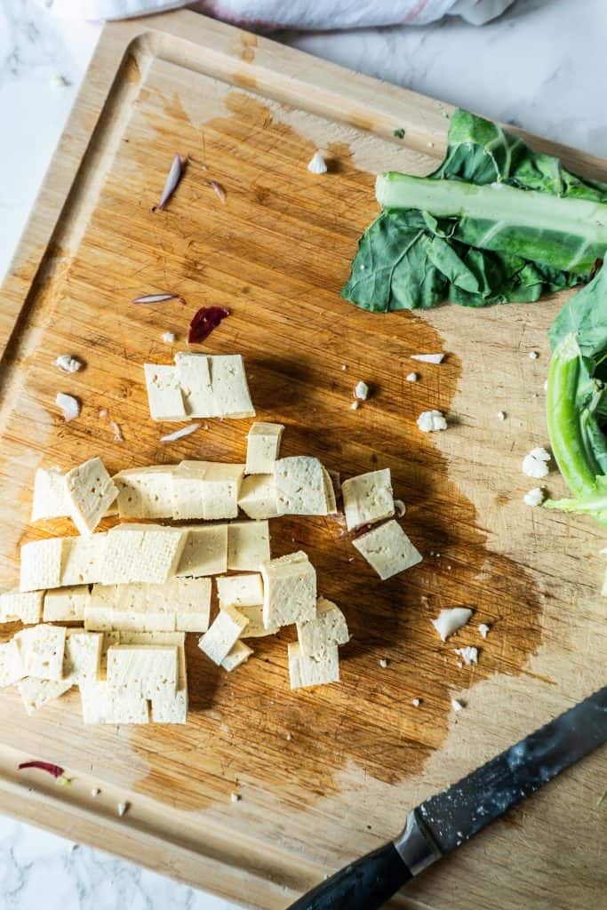 Tofu being chopped on a chopping board